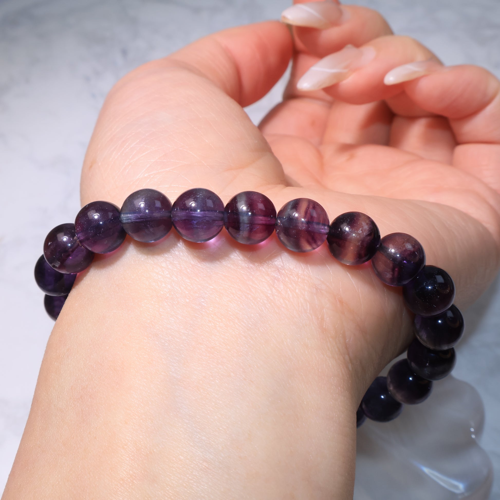 Close-up of fluorite bracelet worn on wrist, showing bead texture and clarity.
