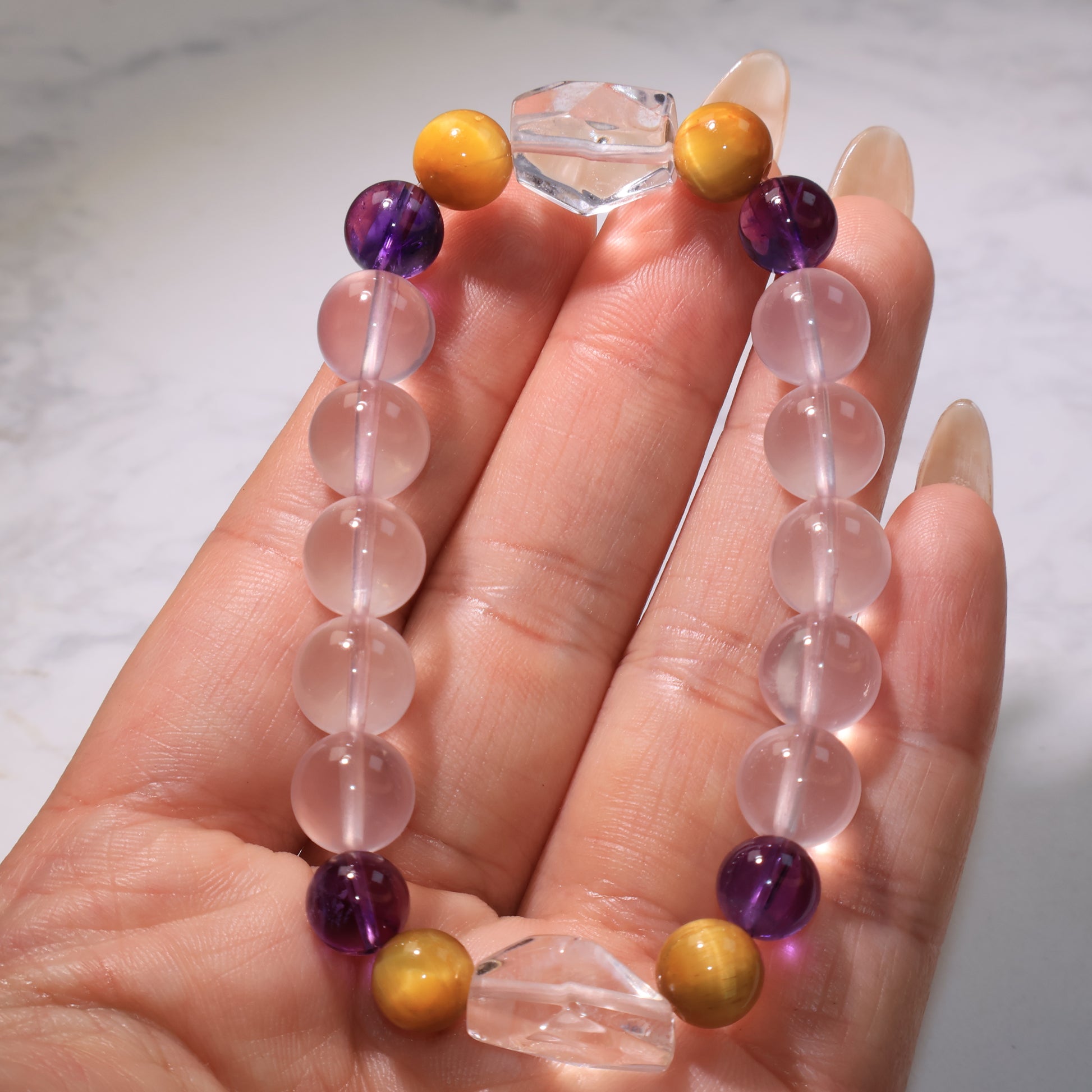 Close-up of the bracelet held in hand, showing the freeform Clear Quartz and colorful beads.