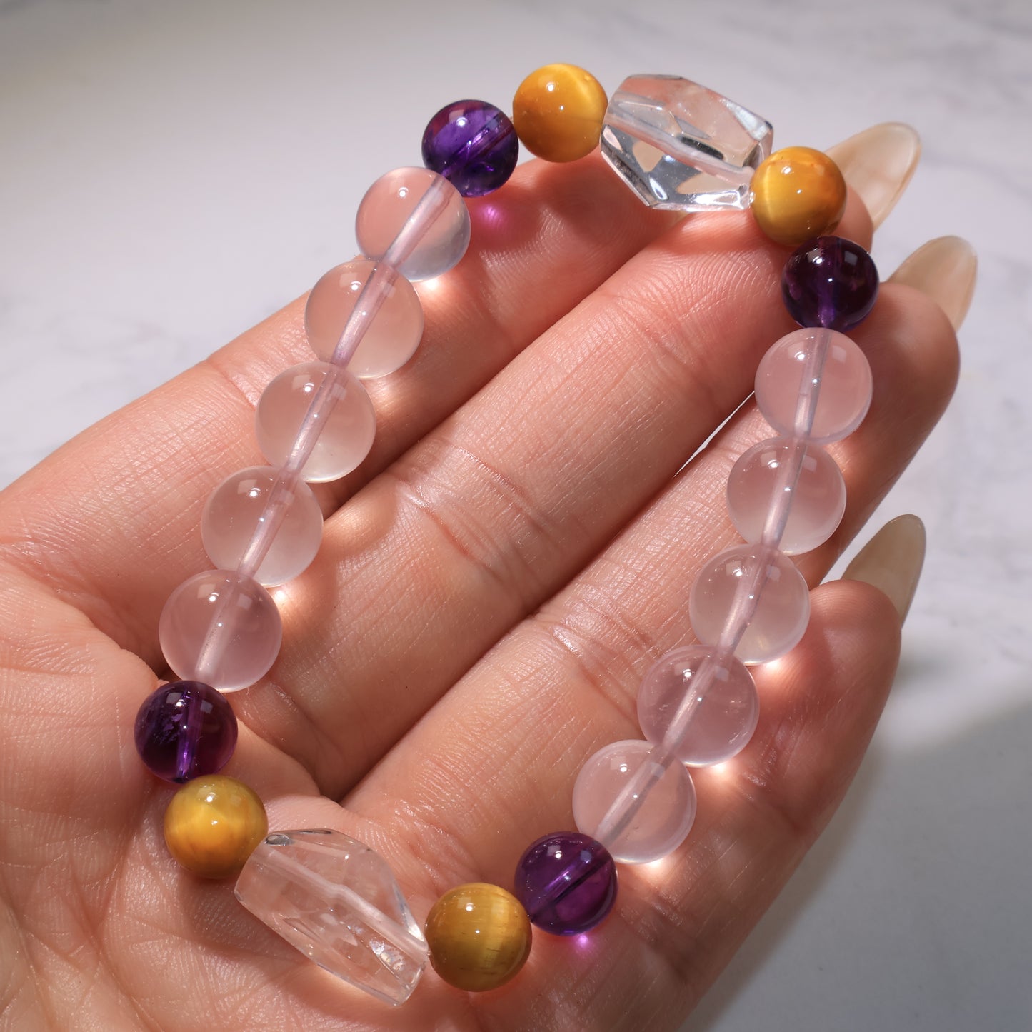 Angle view of the bracelet in hand, highlighting the mix of Rose Quartz, Amethyst, and Tiger’s Eye.