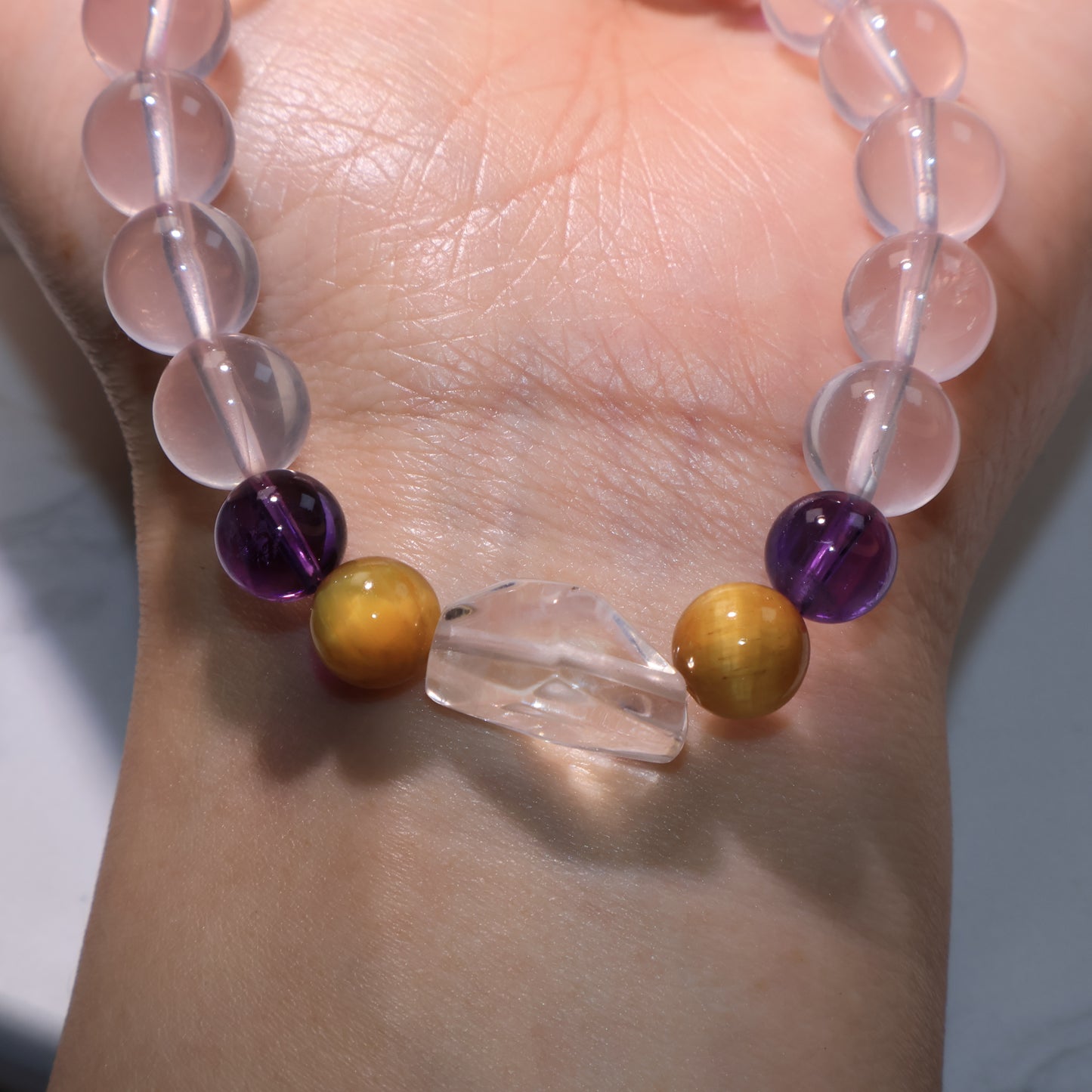 Close wrist view emphasizing the glossy Tiger’s Eye and Amethyst beads beside the Clear Quartz