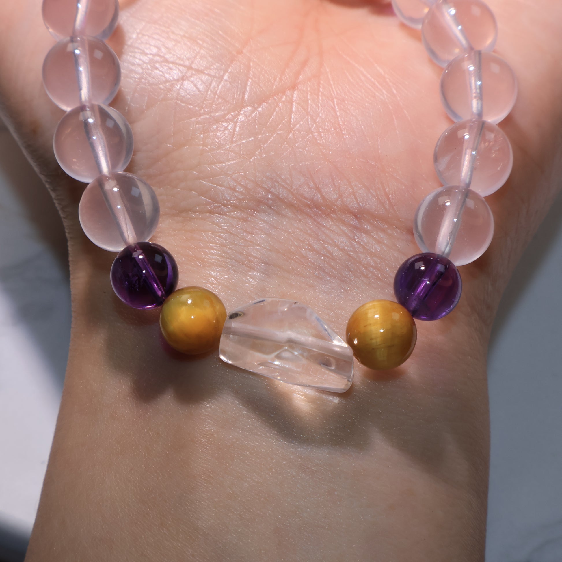 Close wrist view emphasizing the glossy Tiger’s Eye and Amethyst beads beside the Clear Quartz