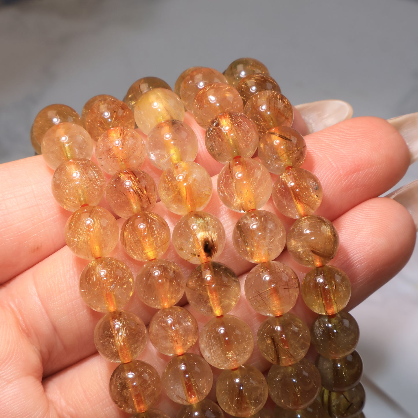 A group of Rutilated Quartz bracelets with shimmering golden-red threads under light.
