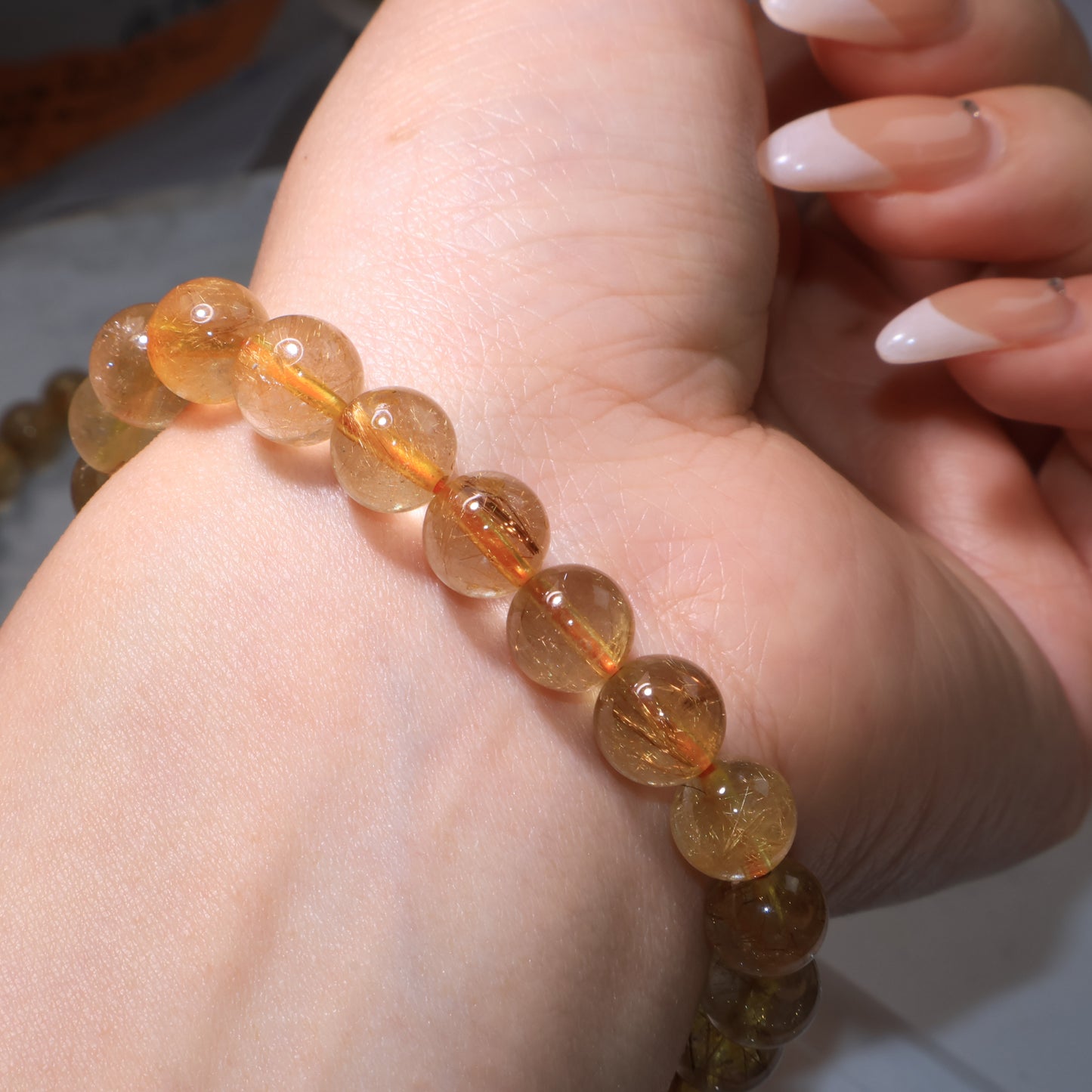 Side view of Rutilated Quartz bracelet on wrist, rutile threads shining inside beads.