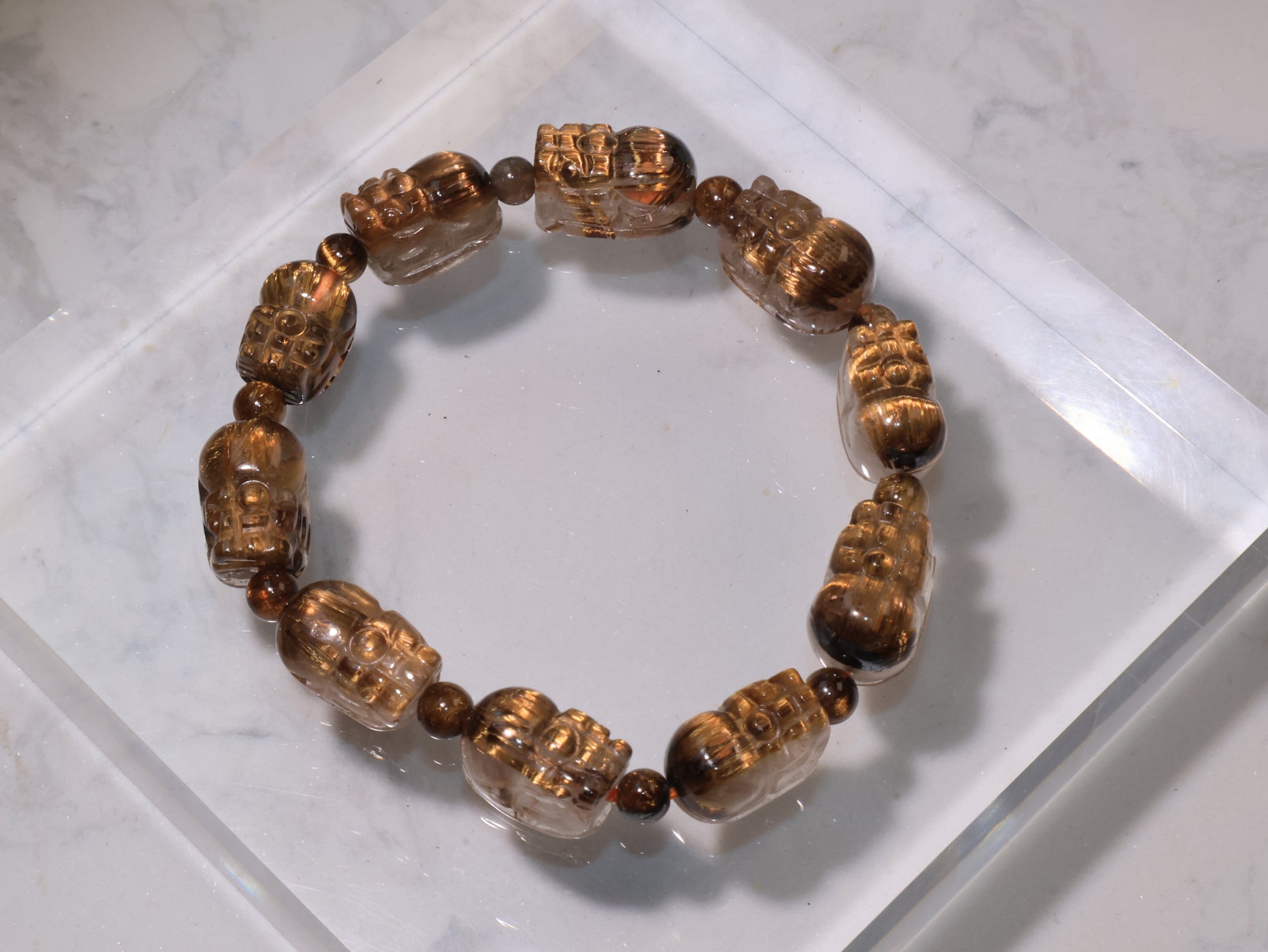 Golden Rutilated Quartz Pixiu Bracelet displayed on acrylic base, showing its golden sheen and clarity.