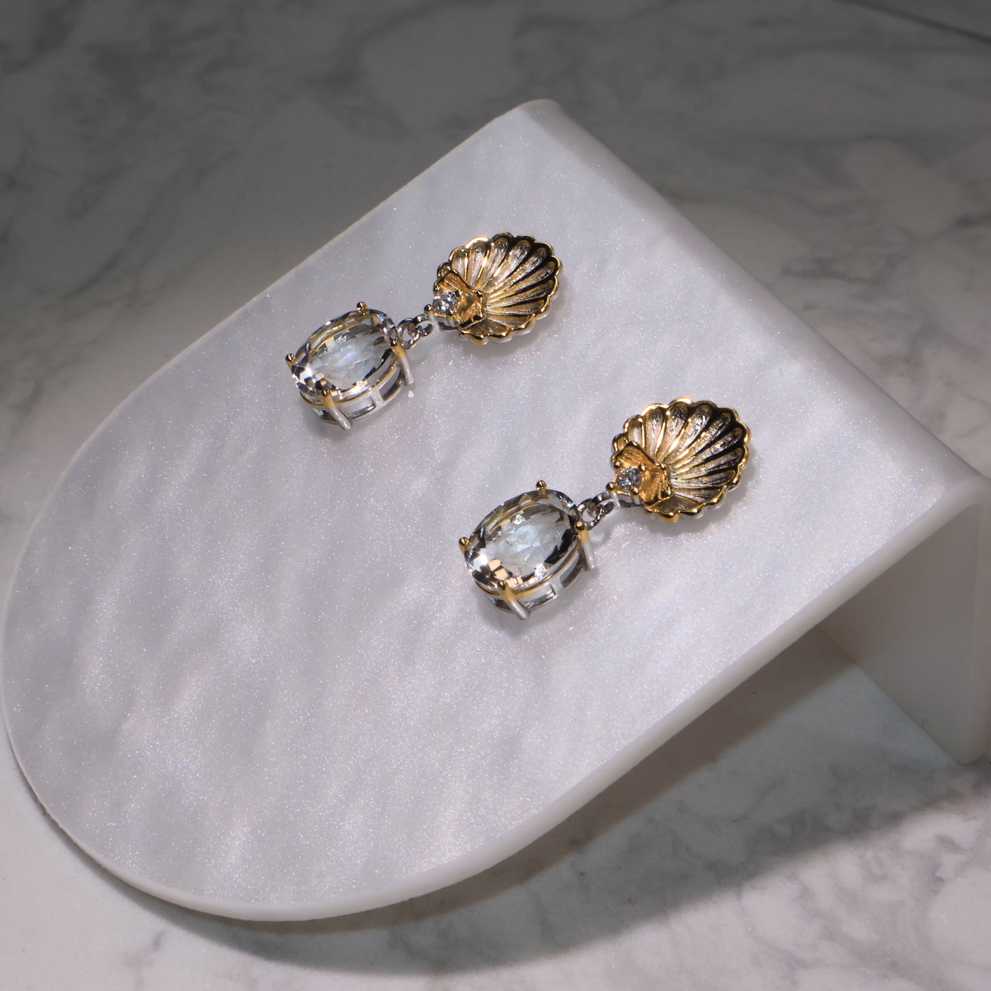 Close-up of the earrings highlighting the crystal clarity and gold shell texture.