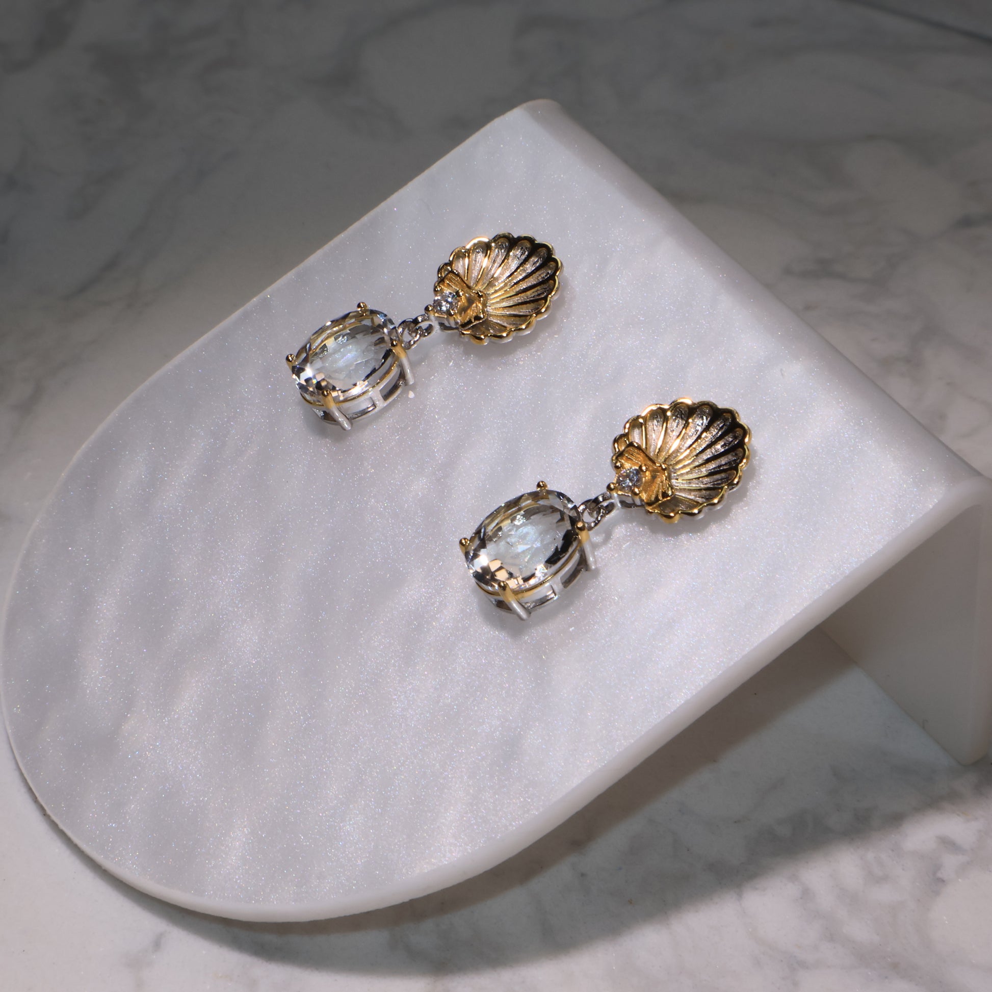 Close-up of the earrings highlighting the crystal clarity and gold shell texture.