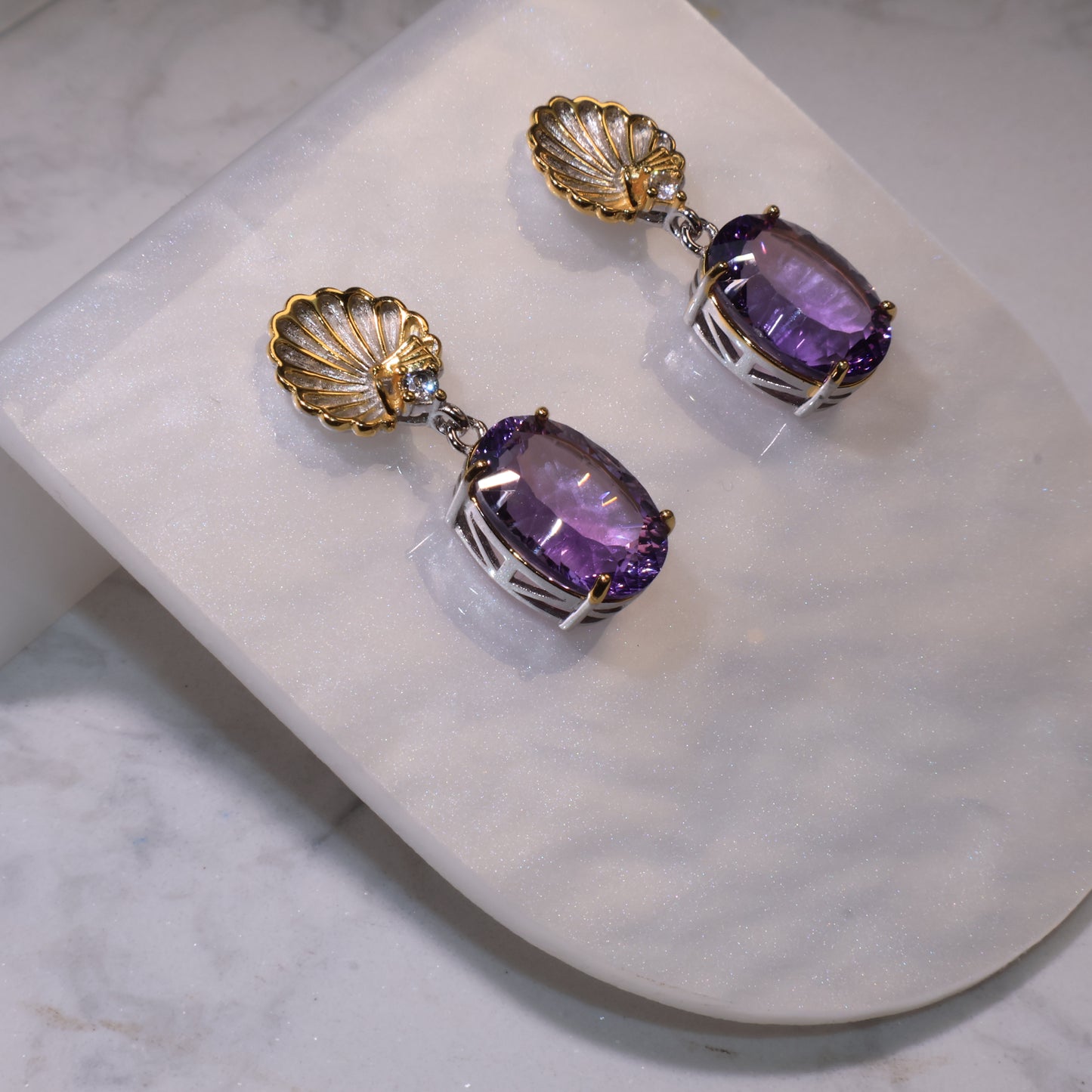 Side view showing the 3D structure of the earrings, highlighting the silver prong setting and amethyst transparency.