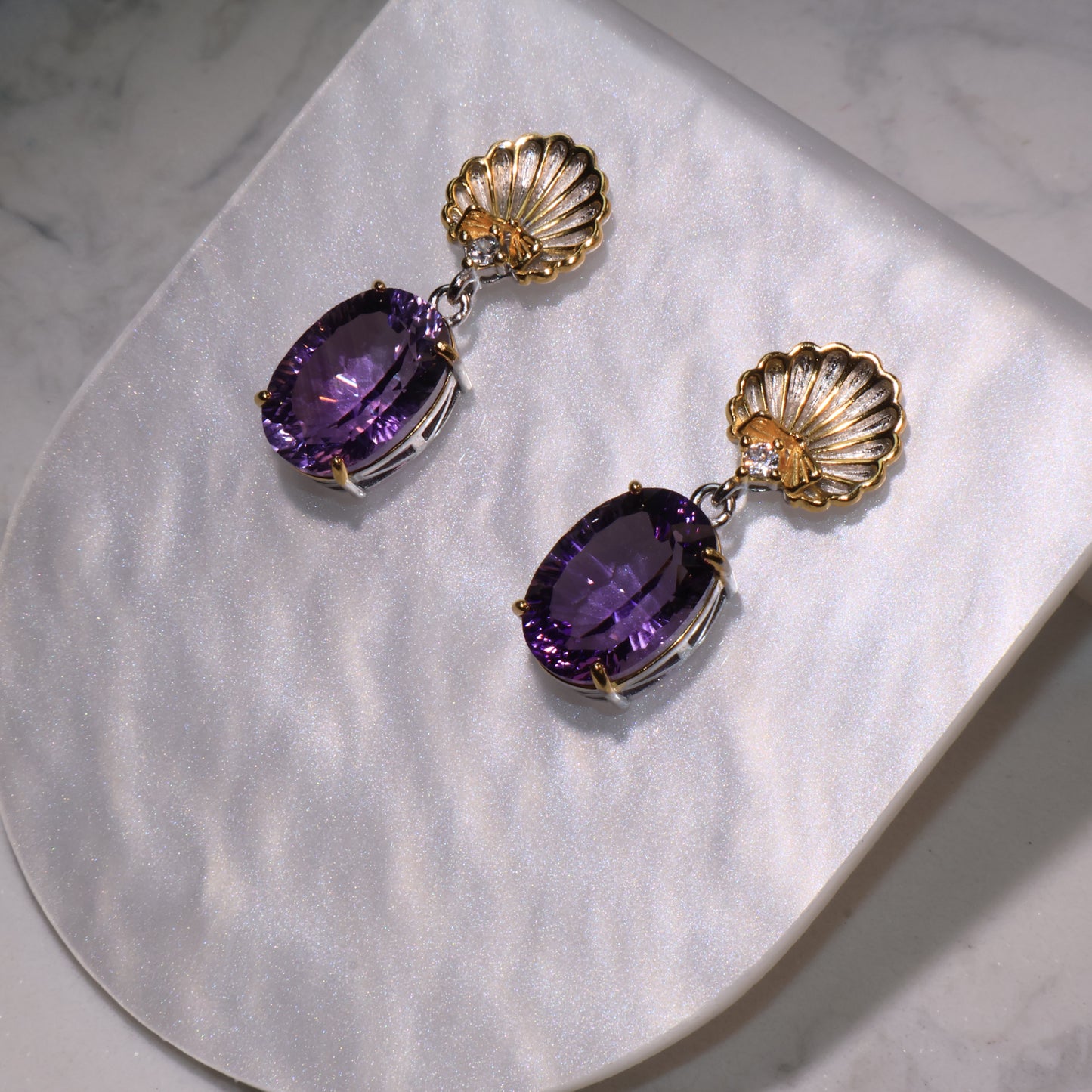 Close-up from above showing the intricate gold shell detail and the vivid brilliance of the oval amethyst stones.