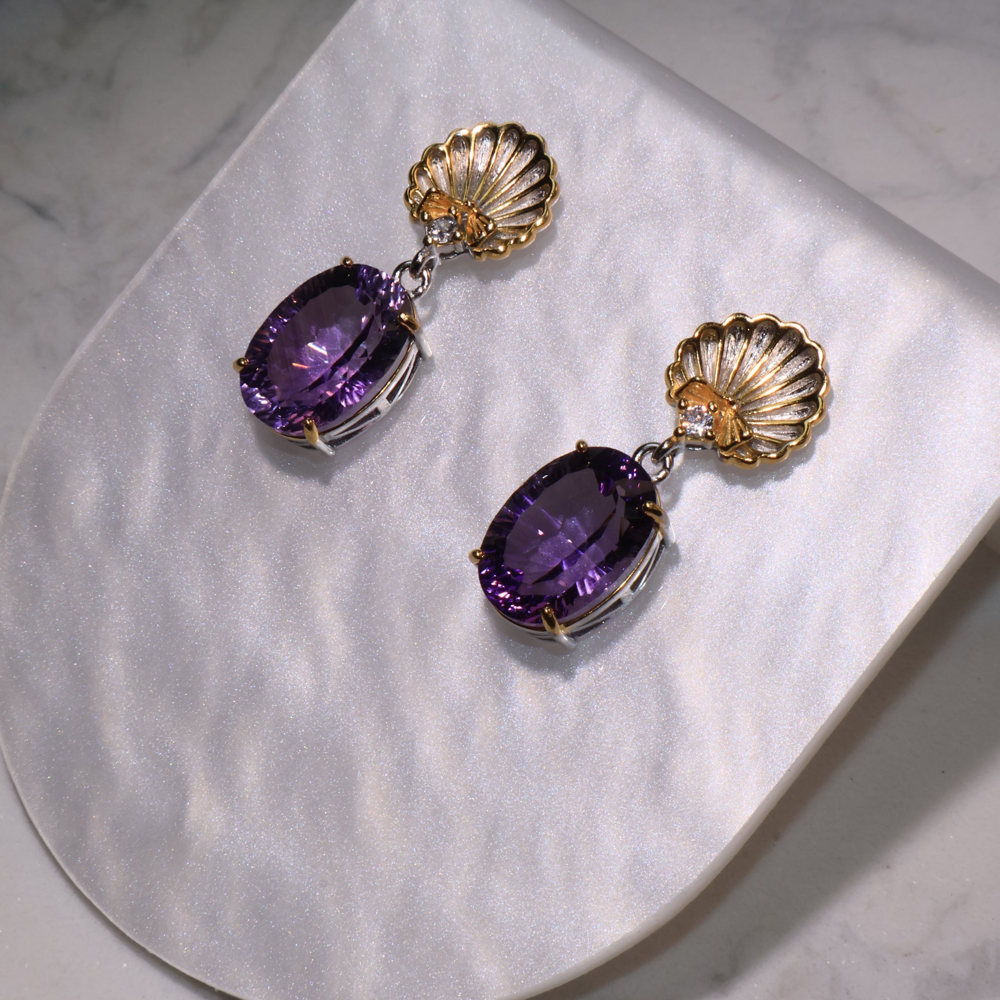 Close-up from above showing the intricate gold shell detail and the vivid brilliance of the oval amethyst stones.