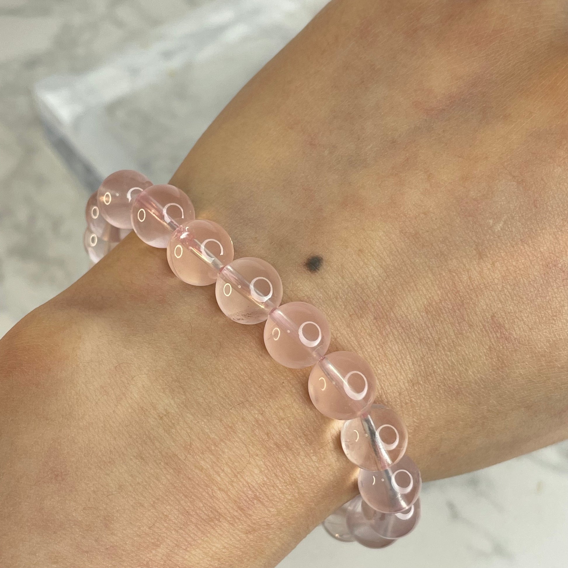 8mm Rose Quartz bracelet worn on wrist, showing soft pink tone against skin