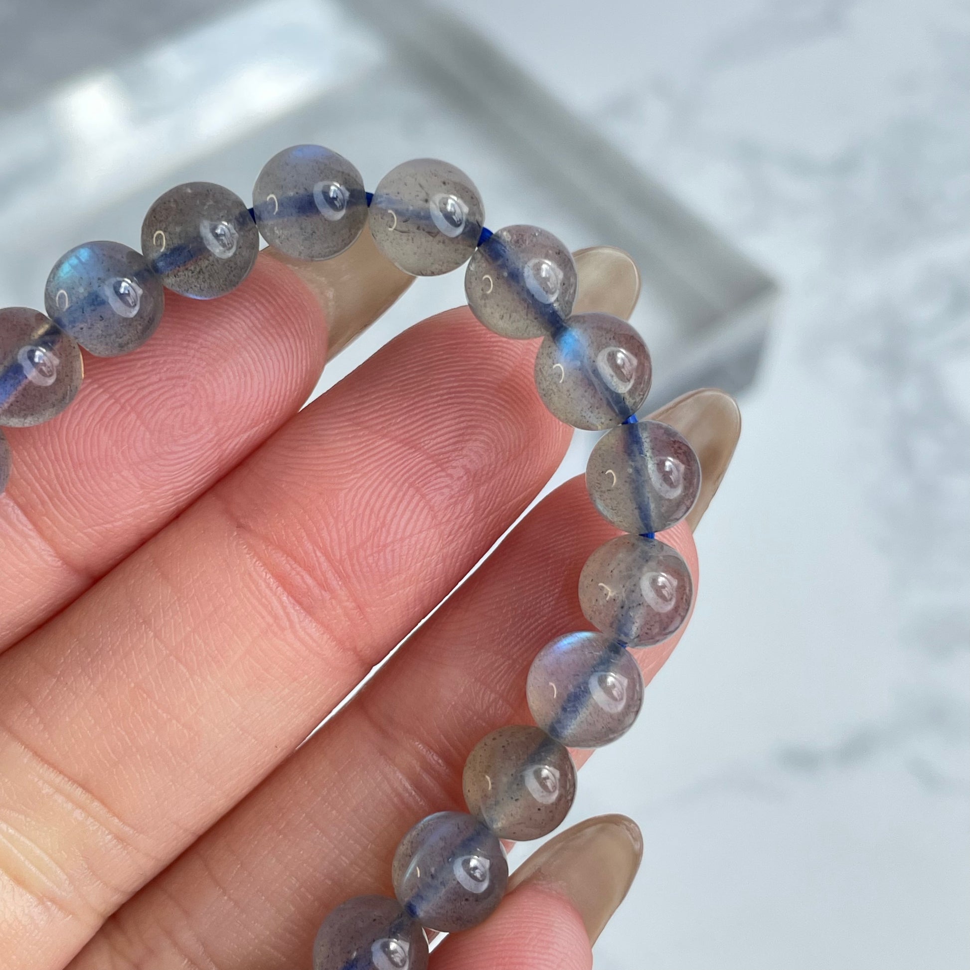 Labradorite glow bracelet with blue flashes – 6mm beads, from Madagascar. Displayed on hand and flat lay with marble background.