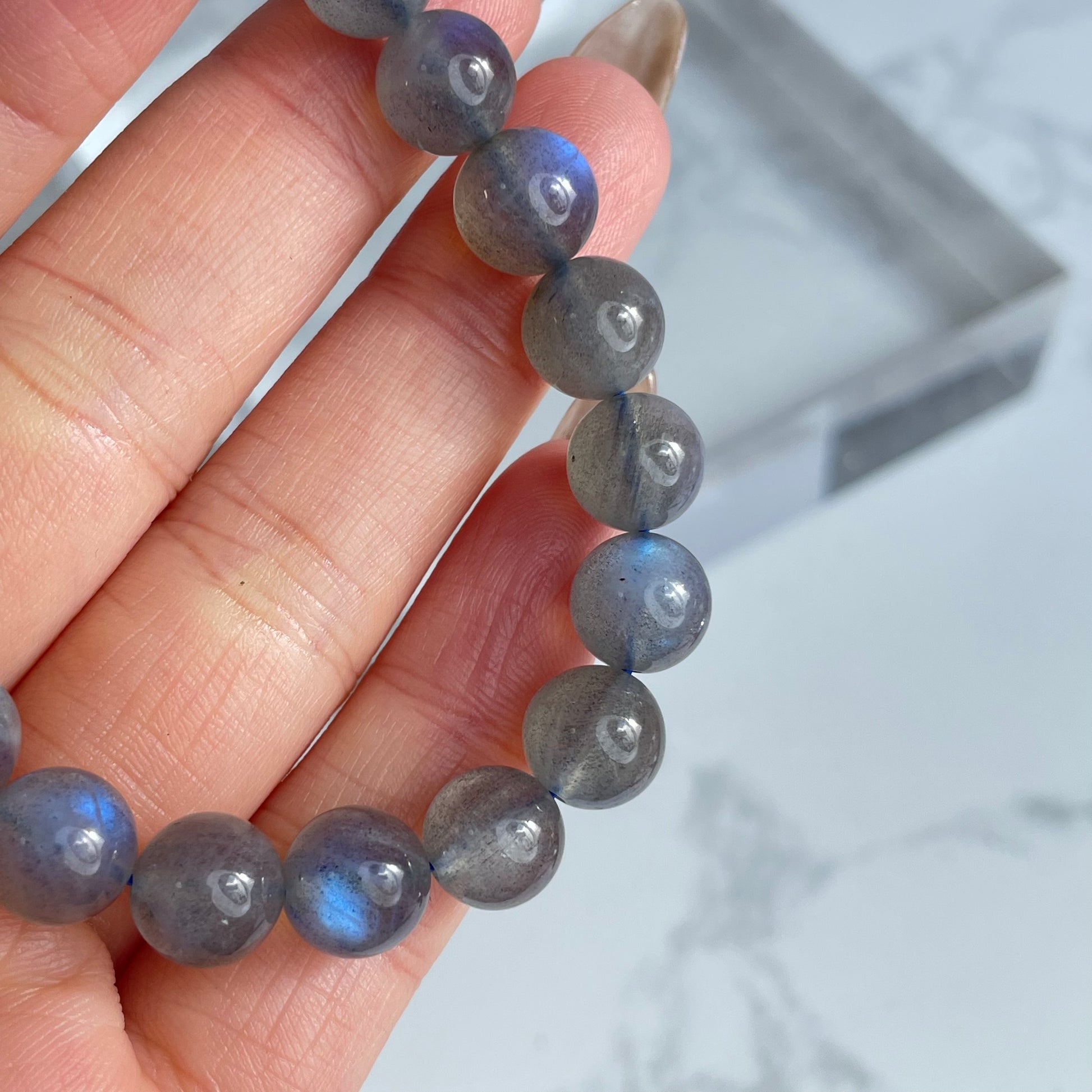 Labradorite bracelet close-up showing multiple beads with blue flashes, held in hand.