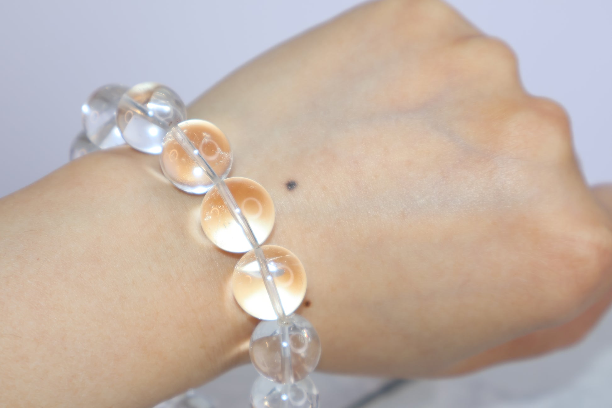 Mystic Clarity Clear Quartz bracelet worn on wrist, showing 14mm beads with high clarity and natural reflection under soft light.