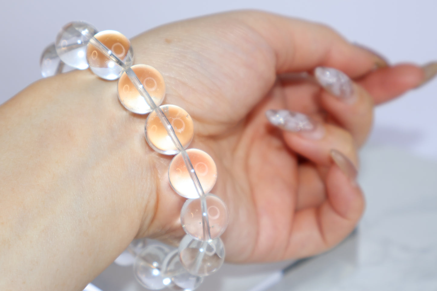 Back view of Mystic Clarity Clear Quartz bracelet worn on wrist, showing full arc of 14mm beads with luminous clarity and soft lighting.