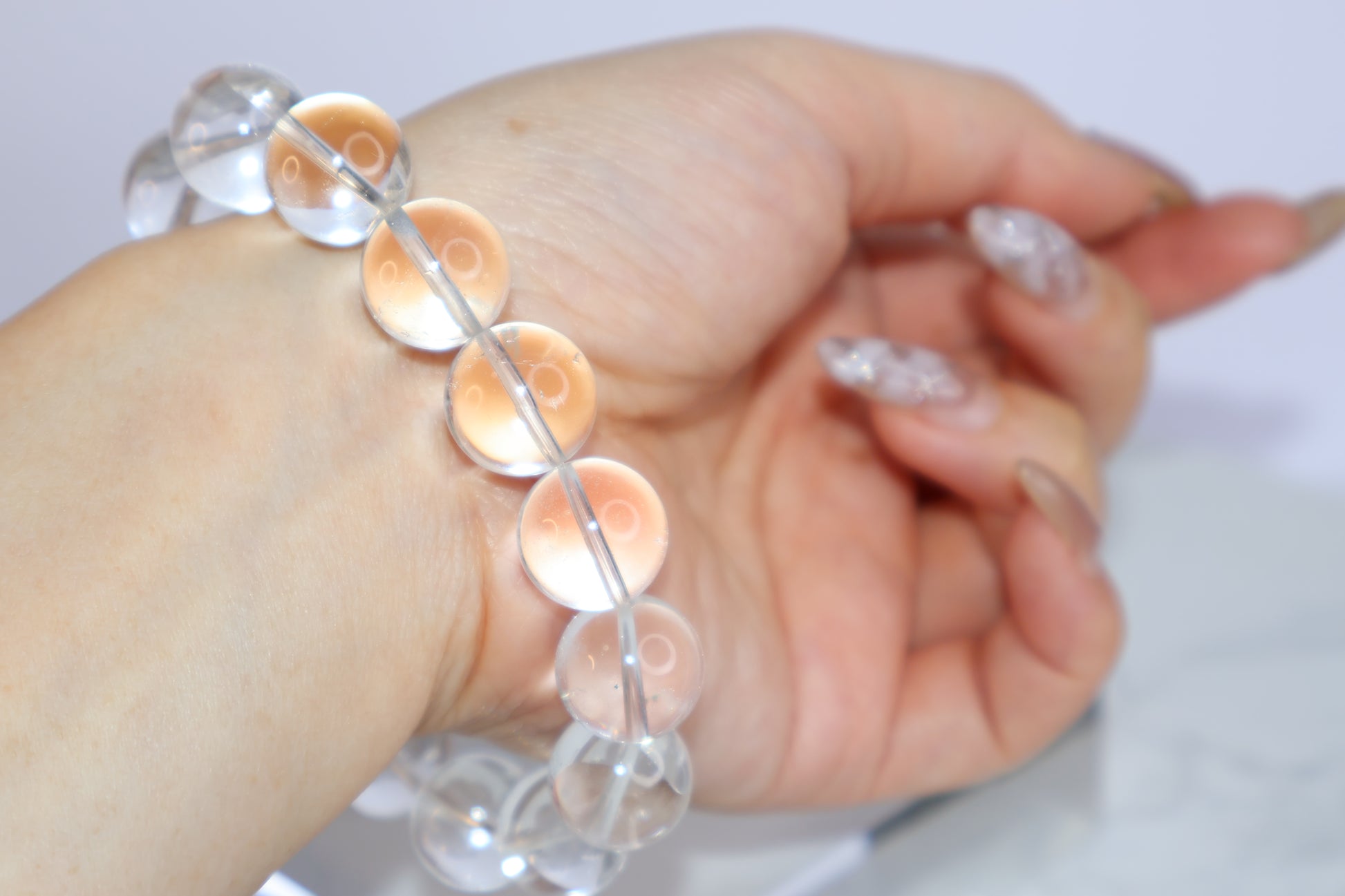 Back view of Mystic Clarity Clear Quartz bracelet worn on wrist, showing full arc of 14mm beads with luminous clarity and soft lighting.