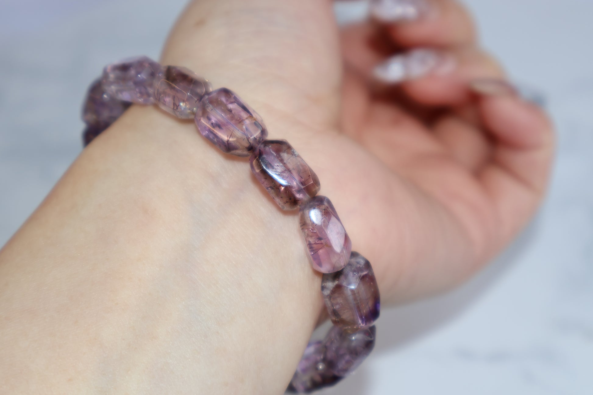 Close-up of Super Seven bracelet with 9mm tumbled beads, showing clarity and rutile inclusions on wrist.