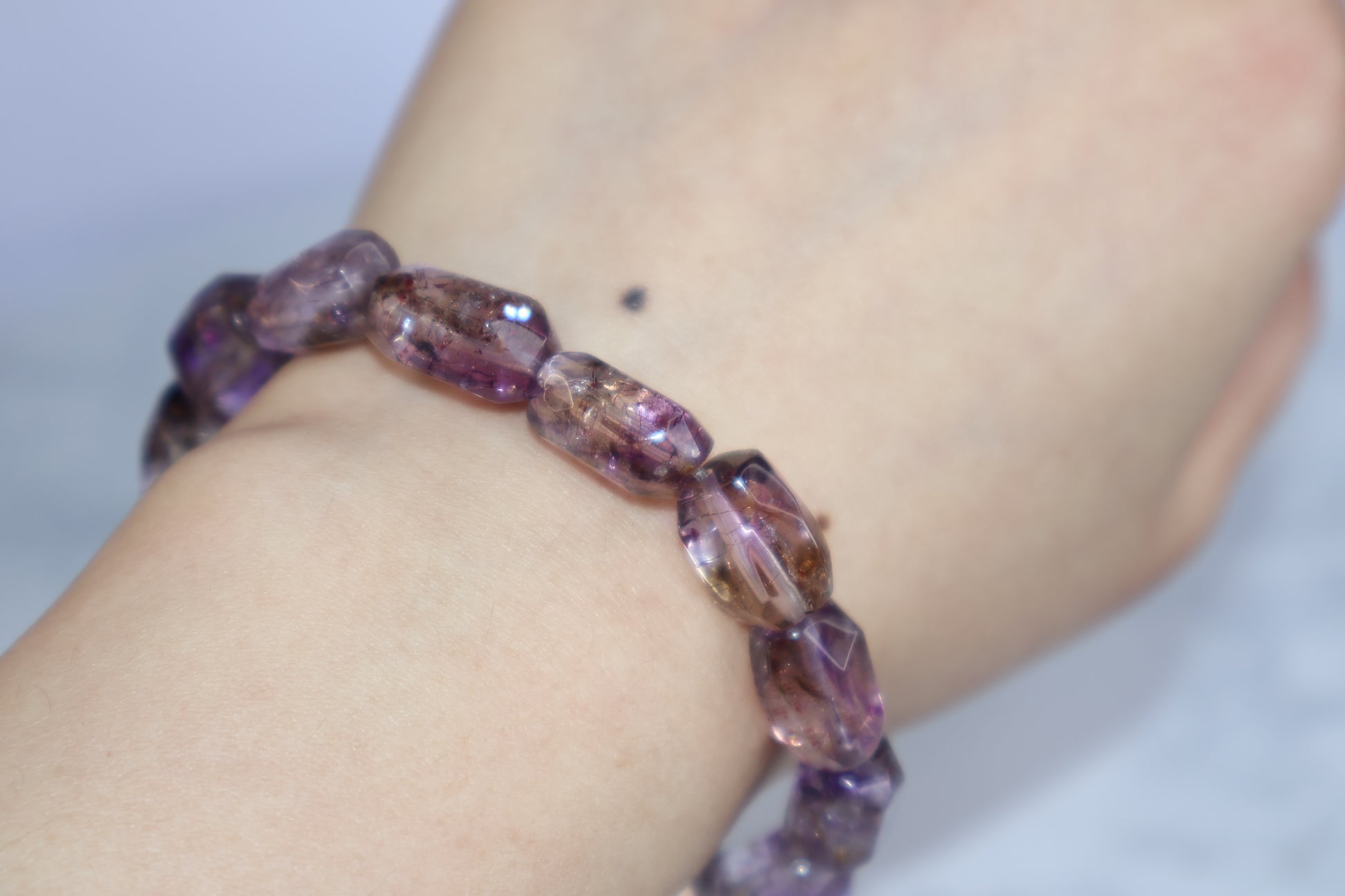 A Super Seven bracelet with clear rutile inclusions worn on wrist, showing natural purple hues and transparency.