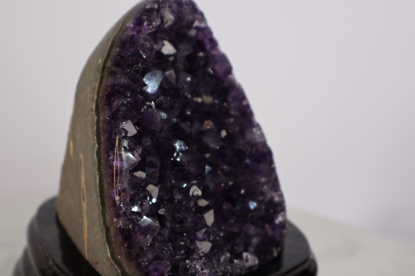 Close-up of a deep purple amethyst geode showing sparkling crystal points and a visible “God’s fingerprint” pattern on the surface.