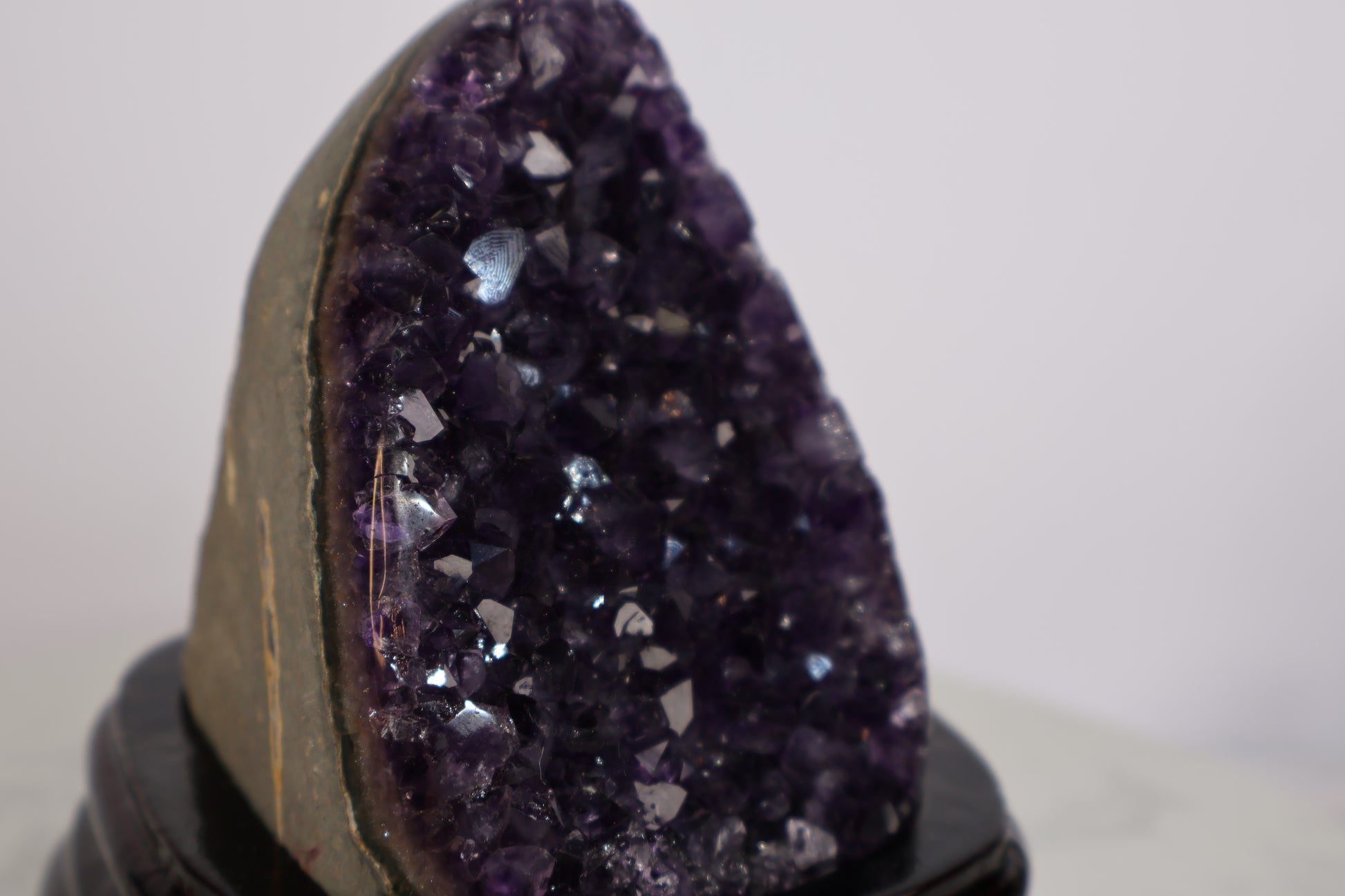 Close-up of a deep purple amethyst geode showing sparkling crystal points and a visible “God’s fingerprint” pattern on the surface.
