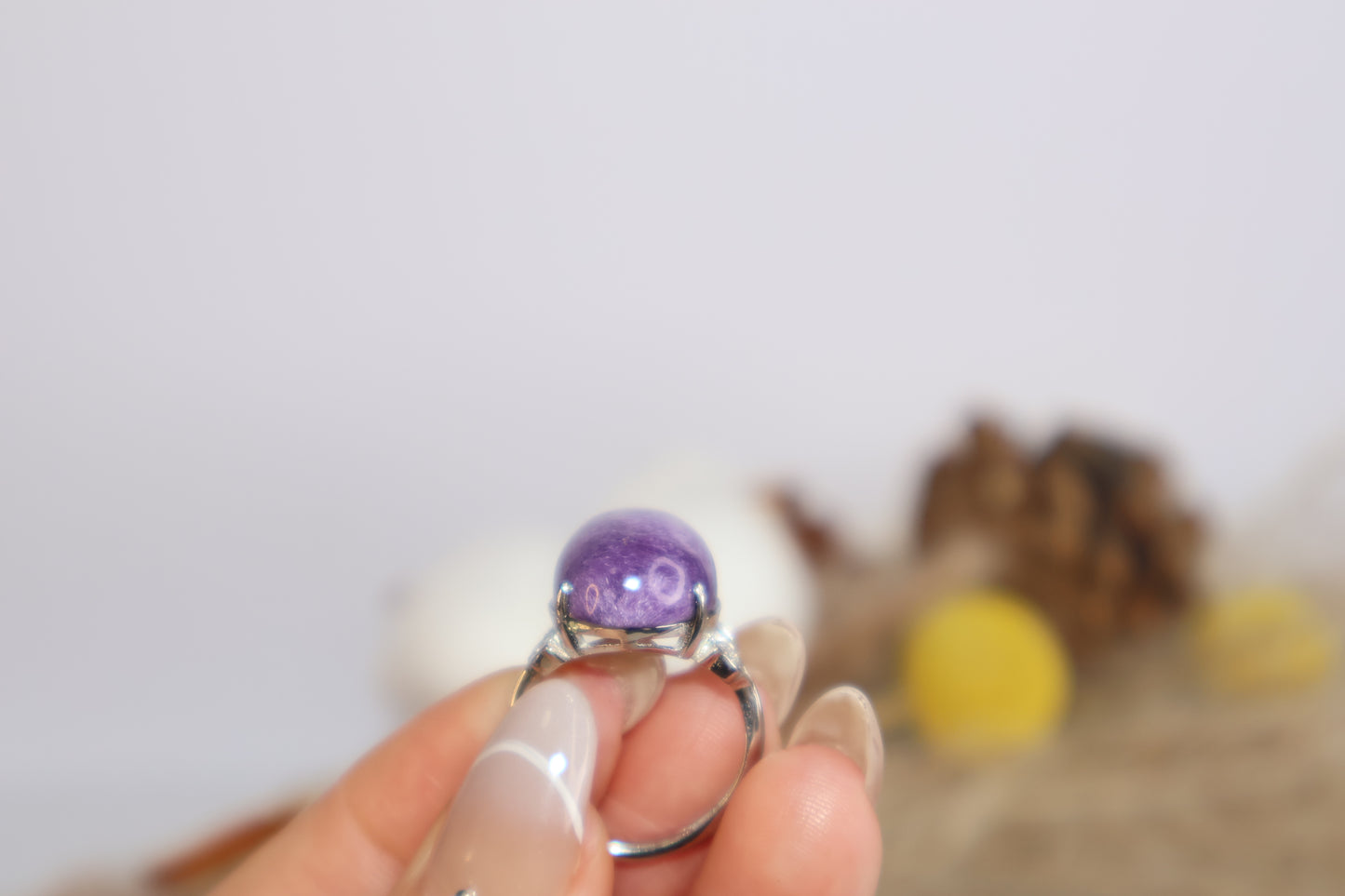 Natural lighting shot of purple charoite crystal ring being held for detail view