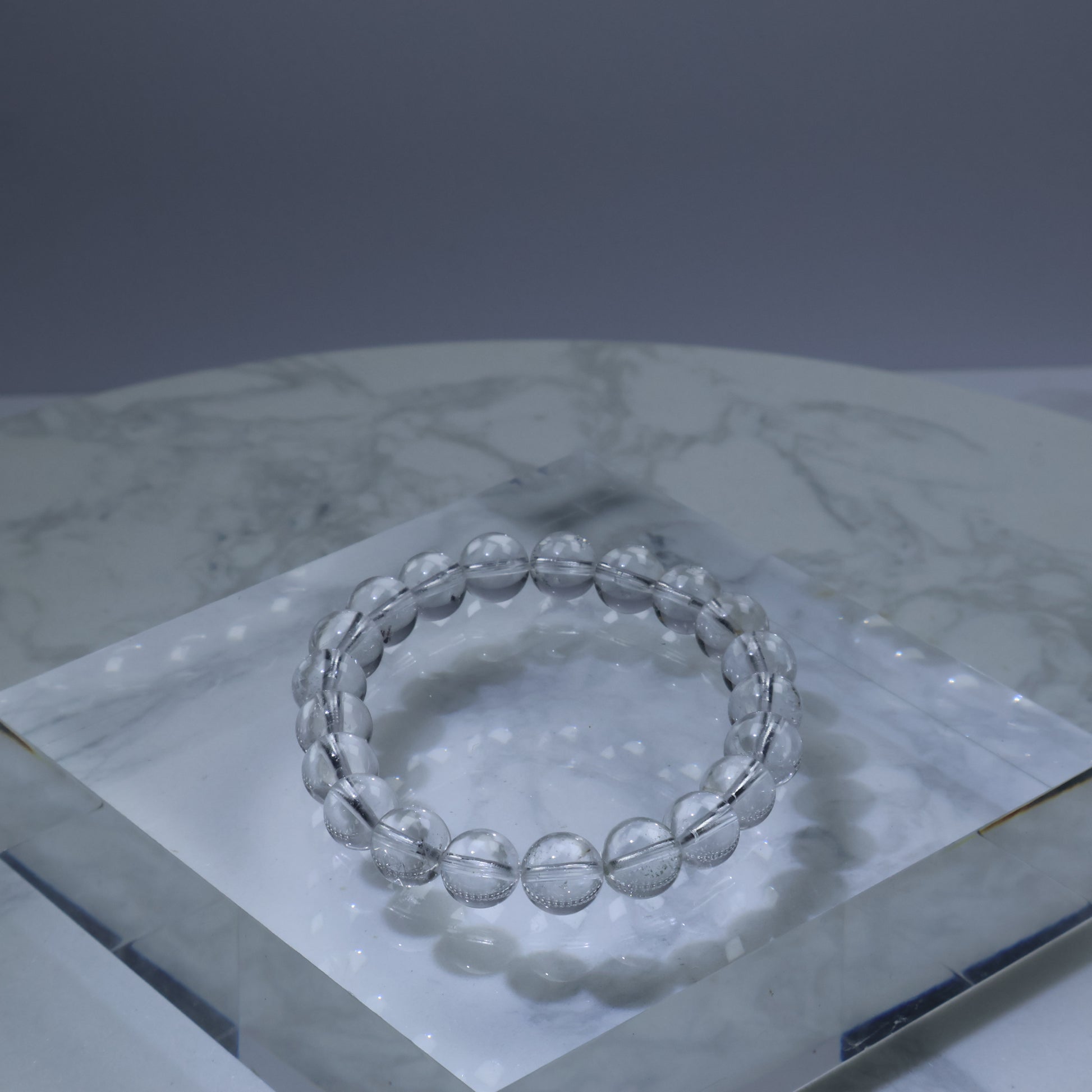 Clear quartz bracelet with 9mm round beads on acrylic block – clean and bright finish