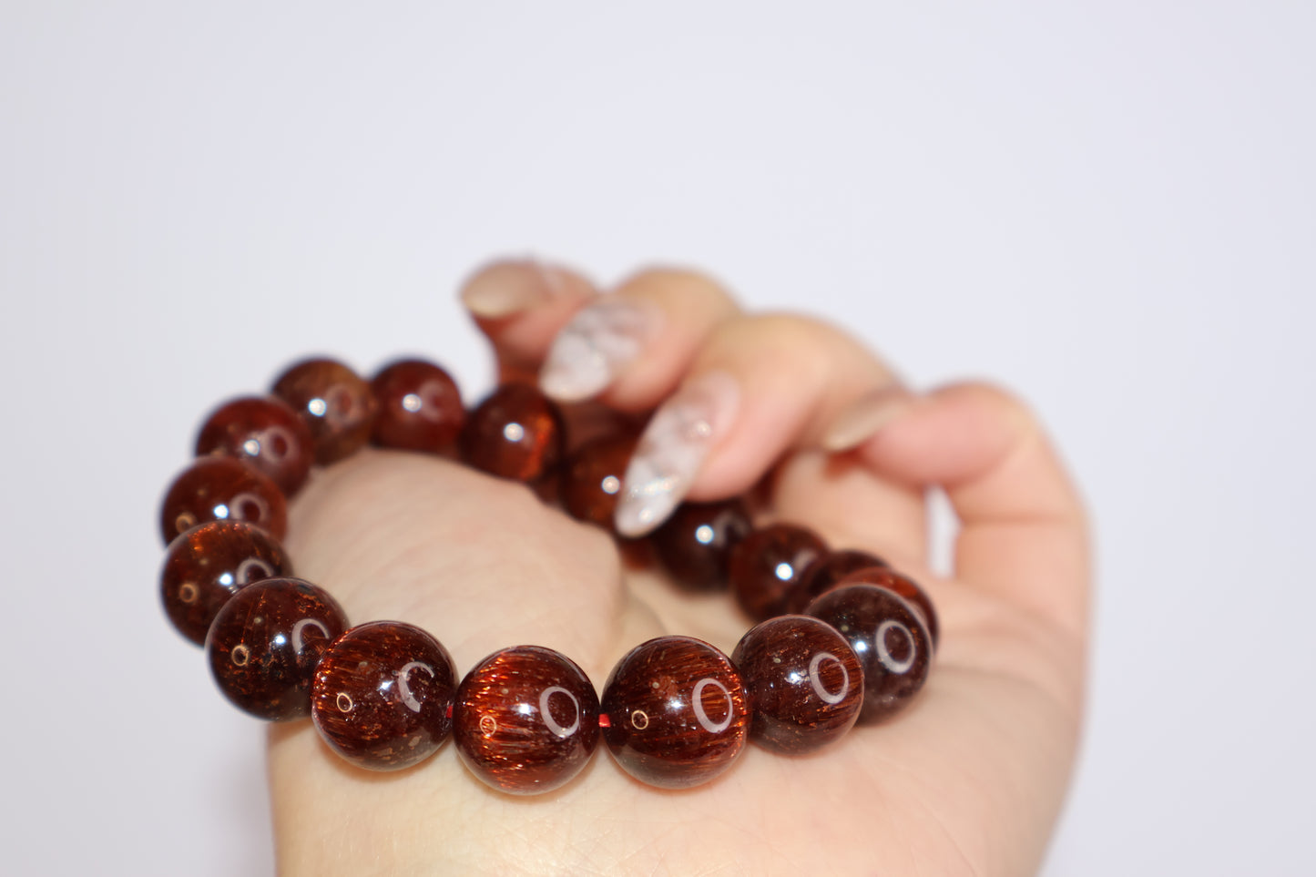 Close-up of Red Rutilated Quartz bracelet with vivid cat’s eye effect, shown wrapped around hand to highlight luster and fine hair-like inclusions, gemstone jewelry for energy and strength.”