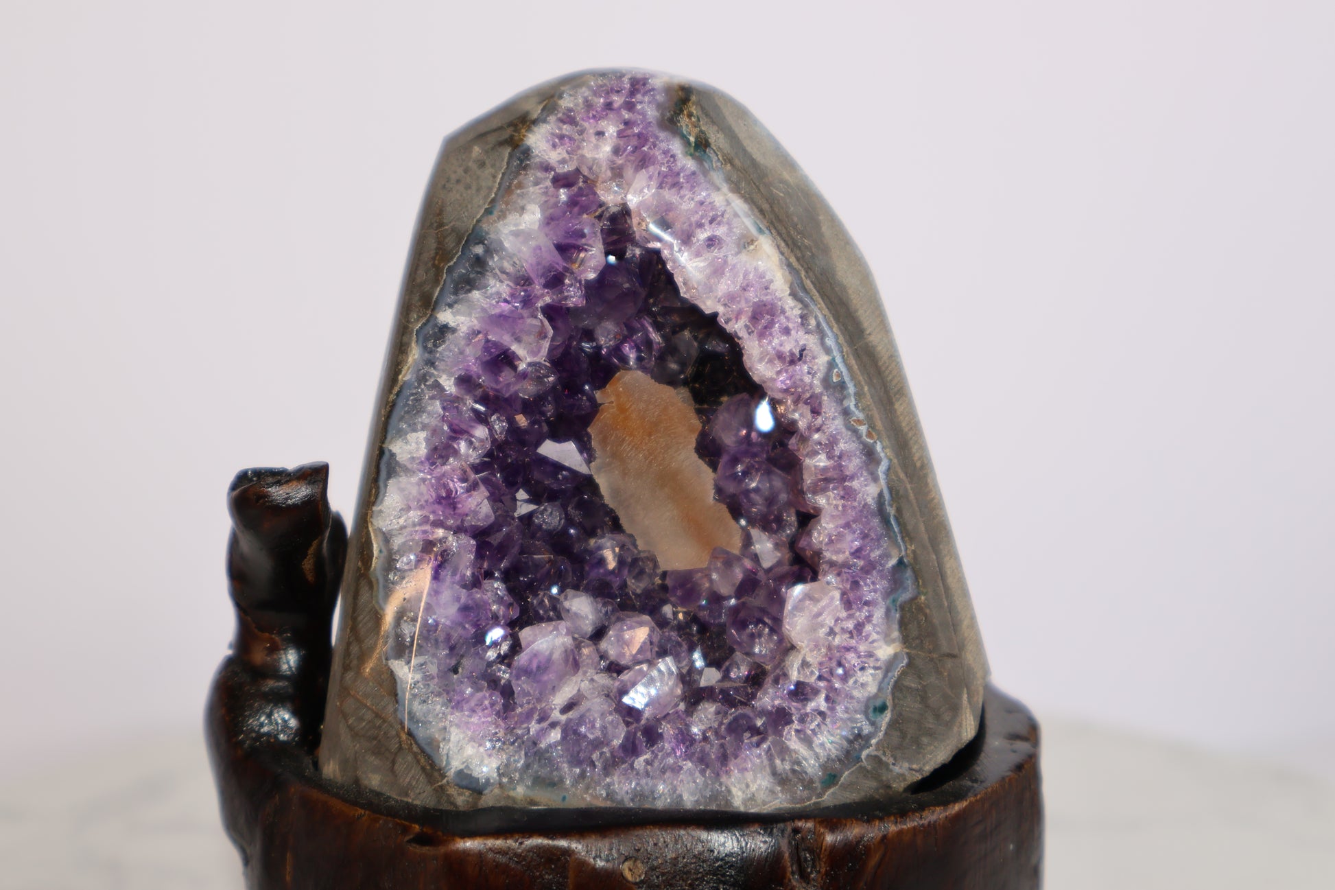 Close-up of amethyst geode with deep purple crystals and orange calcite core on wooden base