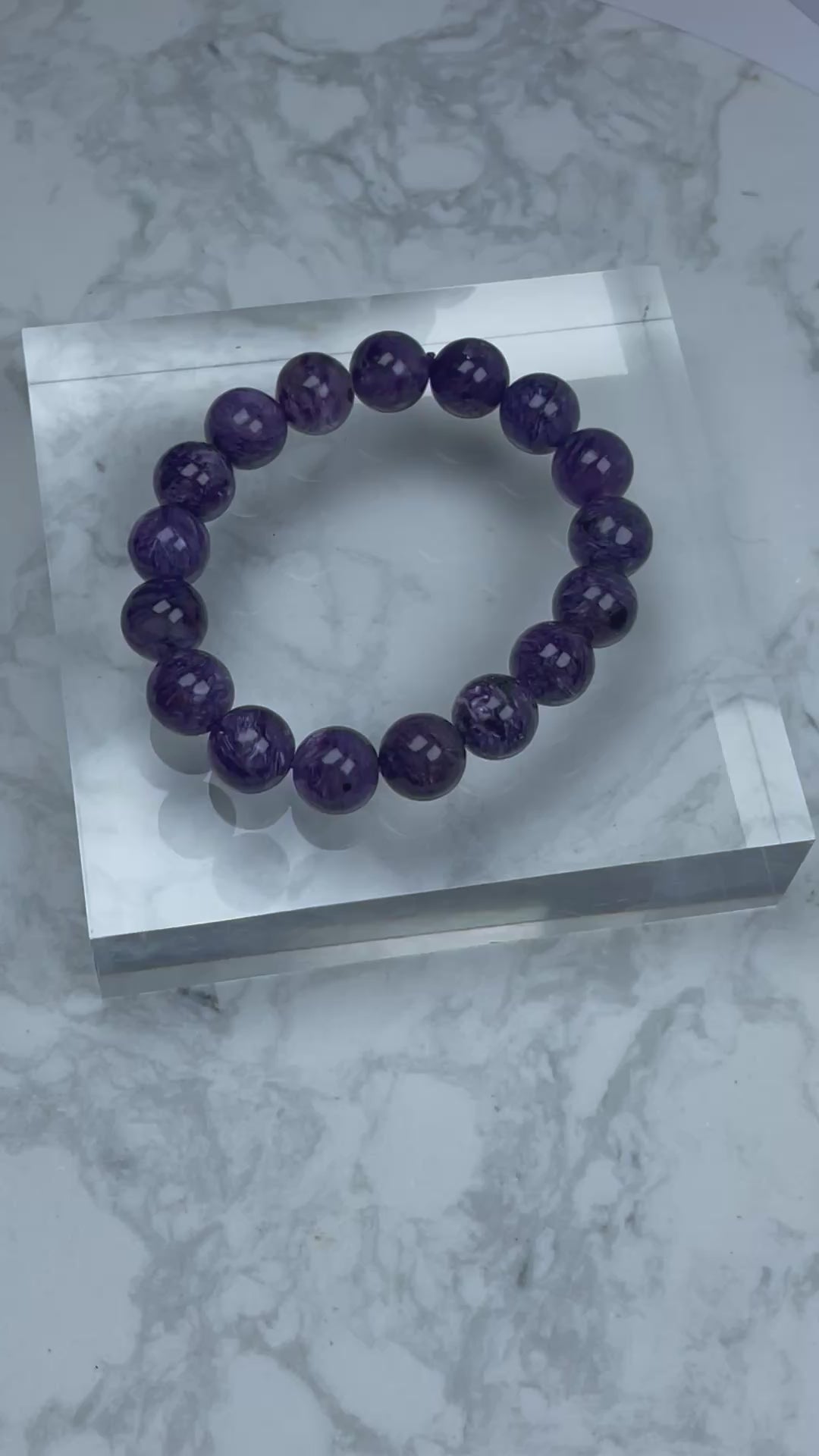 360-degree video showcasing a 12mm Charoite bracelet with deep purple hues and silky swirling patterns, highlighting the natural shine and fibrous inclusions of each bead.