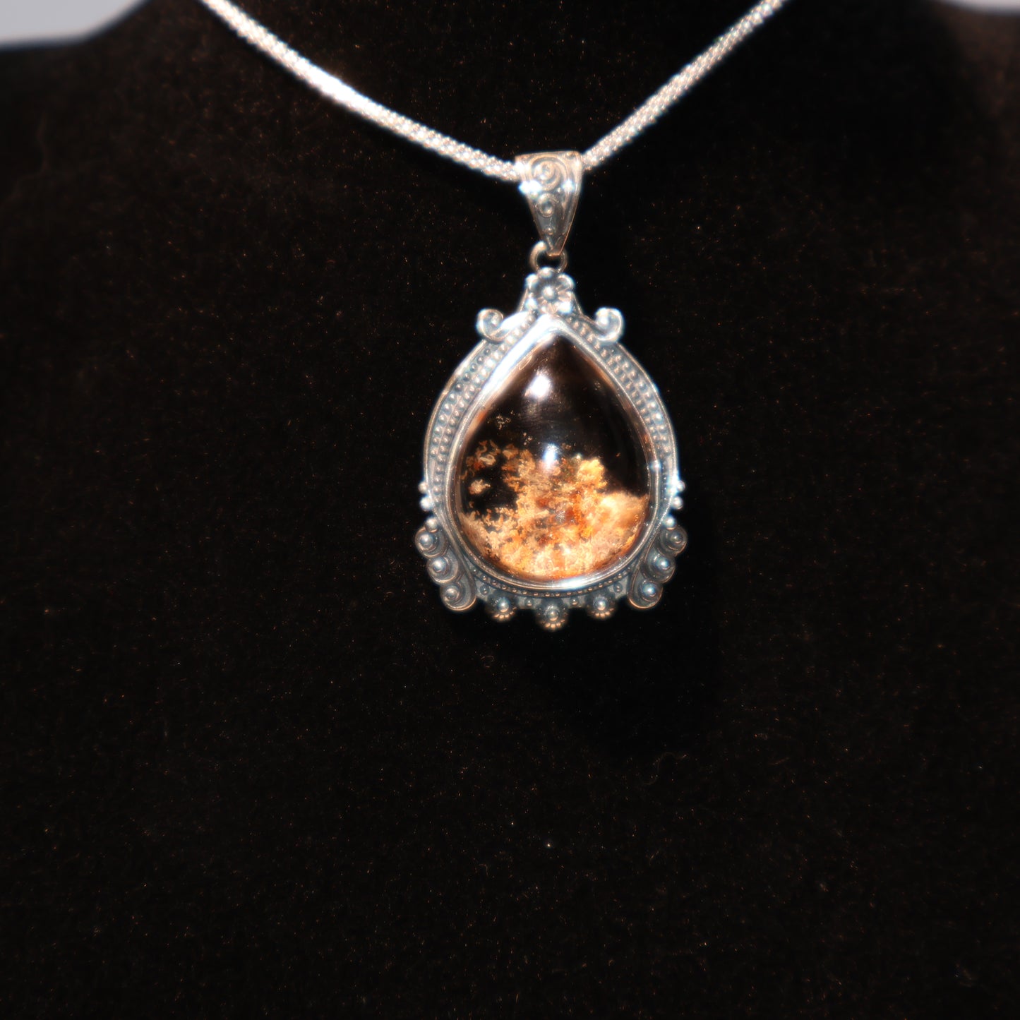 Teardrop-shaped Phantom Quartz pendant with deep reddish-brown inclusions, set in a detailed vintage-style S925 silver frame, displayed against a black velvet background.