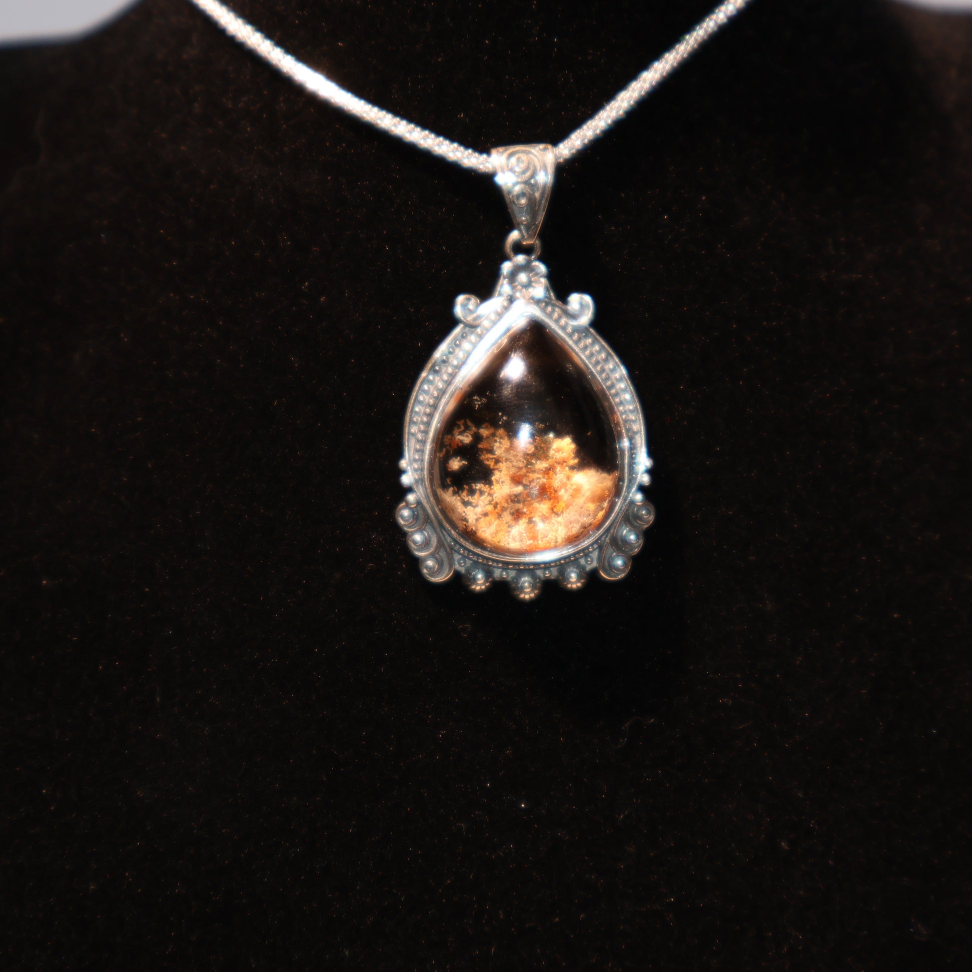 Teardrop-shaped Phantom Quartz pendant with deep reddish-brown inclusions, set in a detailed vintage-style S925 silver frame, displayed against a black velvet background.