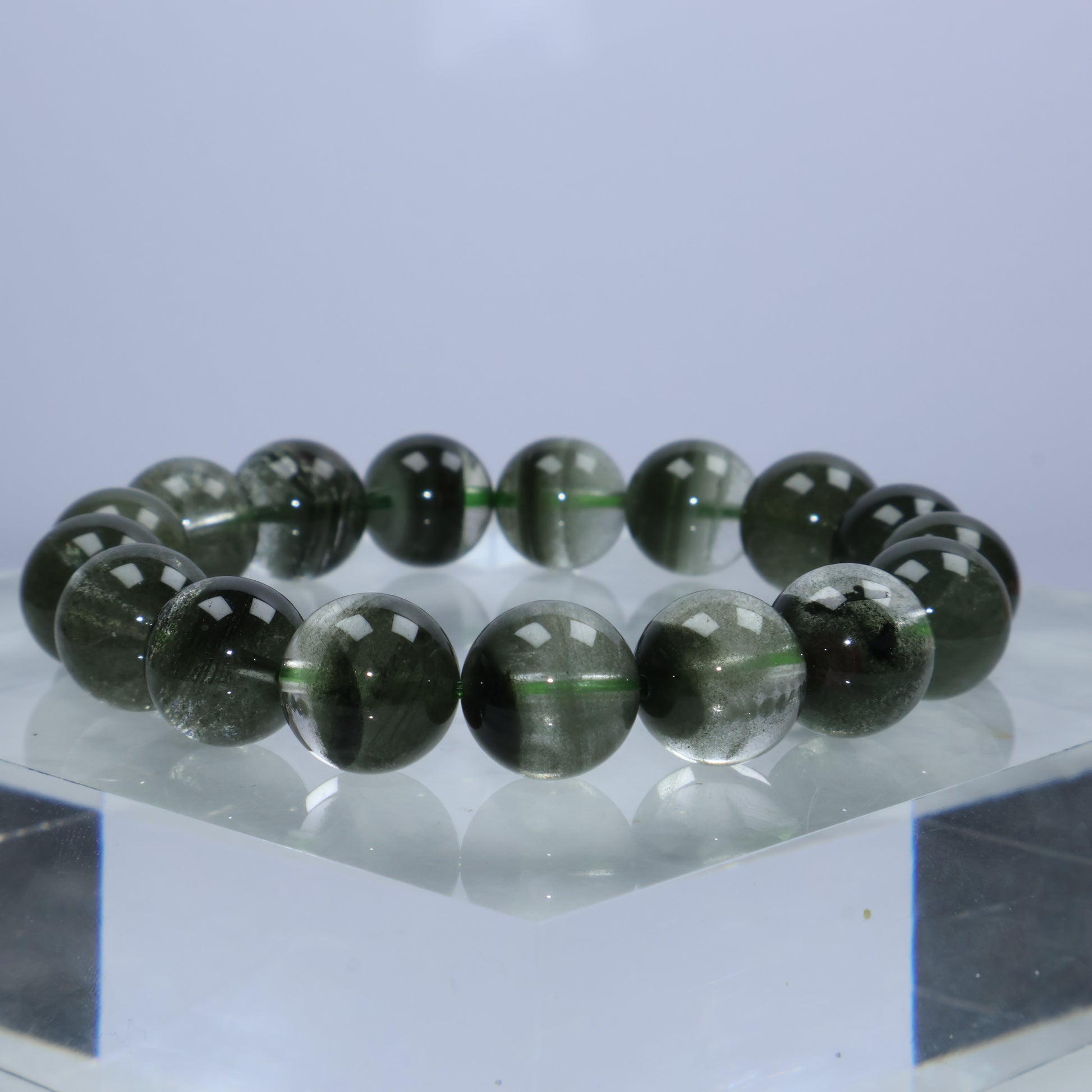 Side angle of the bracelet on acrylic stand highlighting moss-like inclusions