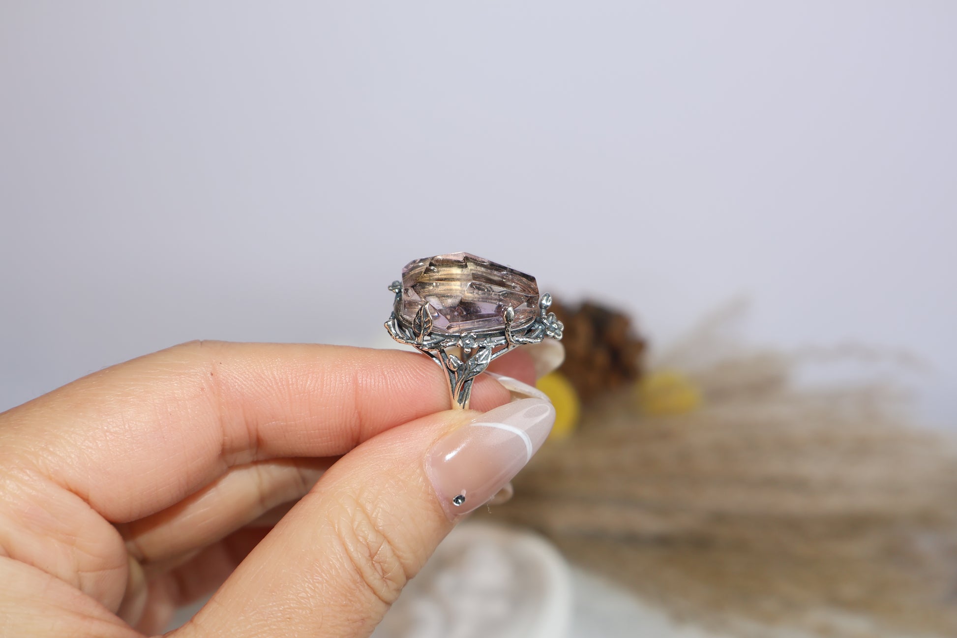 Hand holding the floral oxidized silver ring with faceted Ametrine