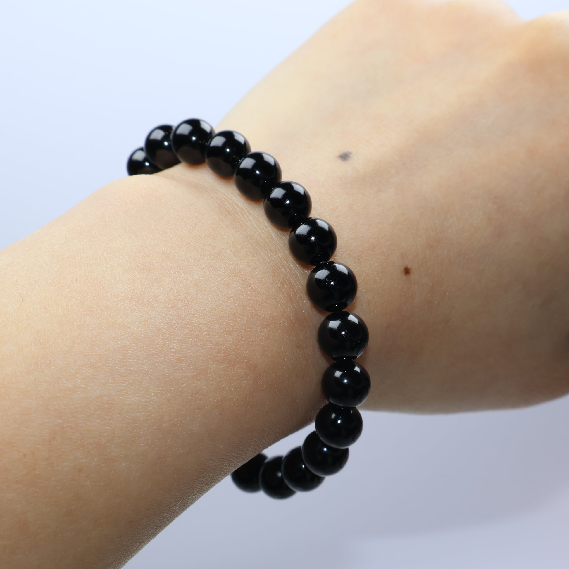 Wrist shot of 7mm Black Obsidian bracelet worn against skin, showing fit and smooth finish