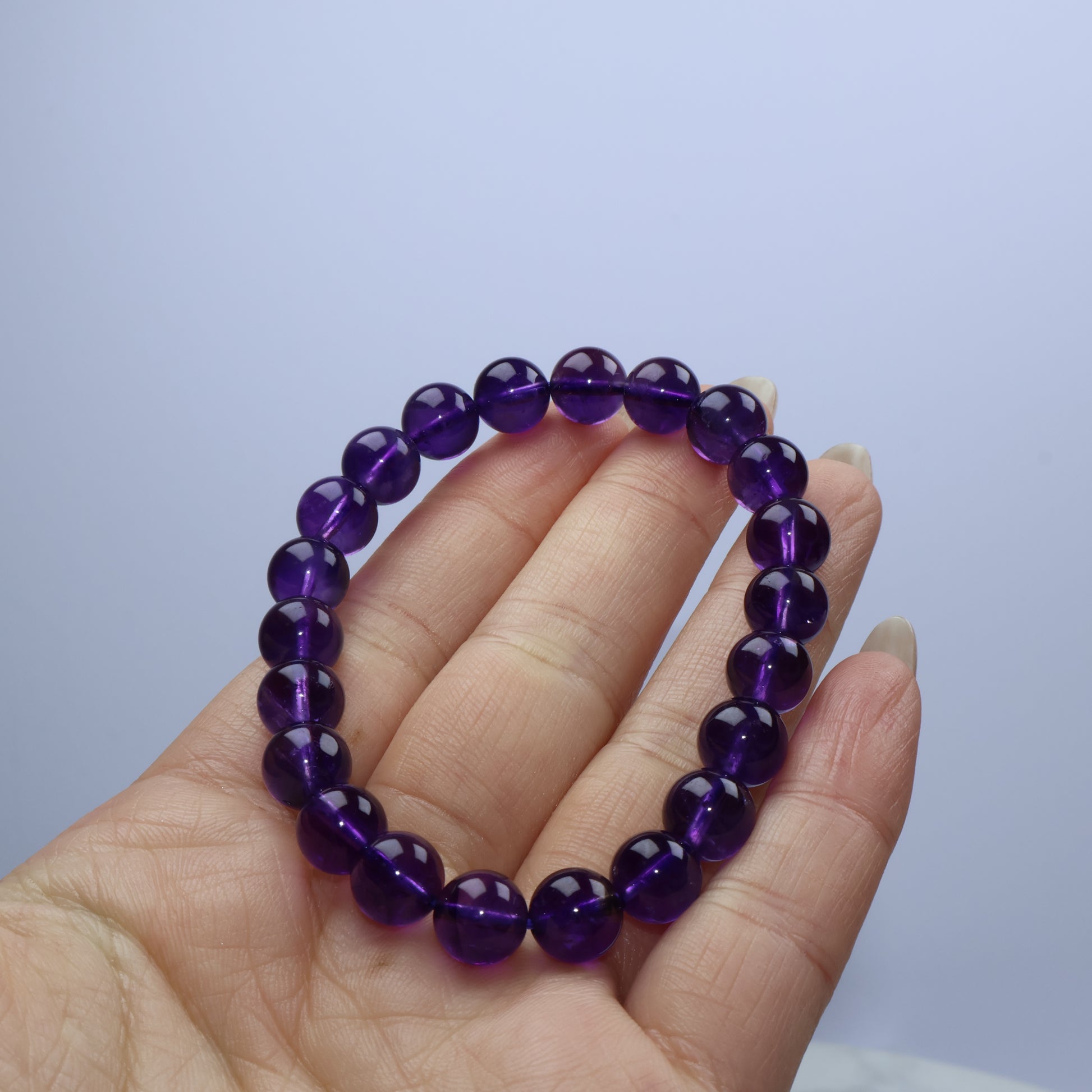 Handheld view of deep violet 8mm Amethyst bracelet from Uruguay