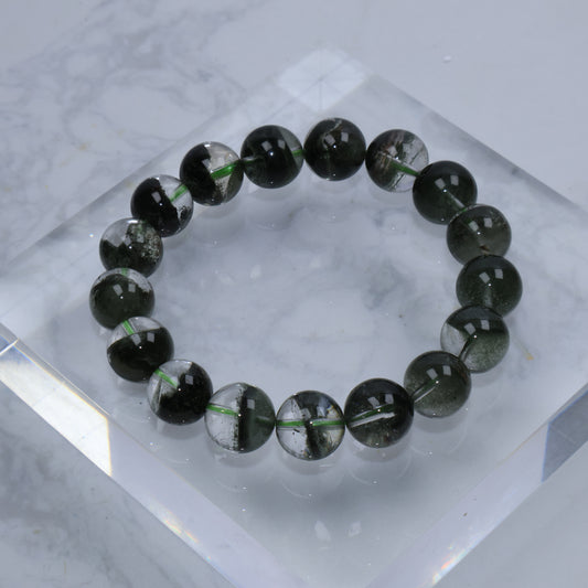 Top-down view of Verdant Path Green Phantom Quartz bracelet – full circle of 12mm round beads showing dark green phantom inclusions inside clear quartz.
