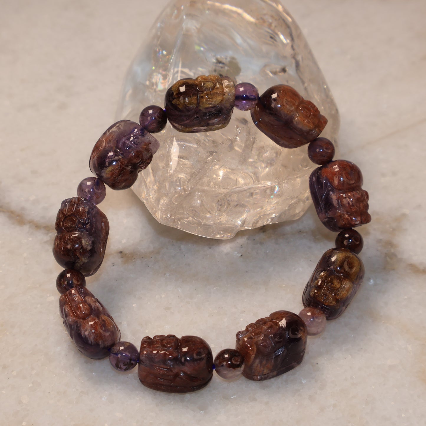 Purple Phantom Quartz Pixiu bracelet displayed with clear quartz crystal on marble background