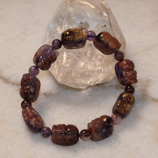 Purple Phantom Quartz Pixiu bracelet displayed with clear quartz crystal on marble background