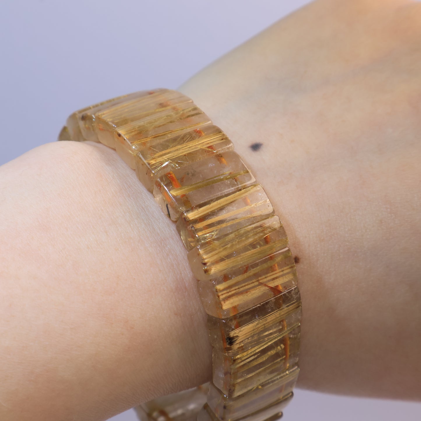 Bracelet glowing warmly on the wrist under light.