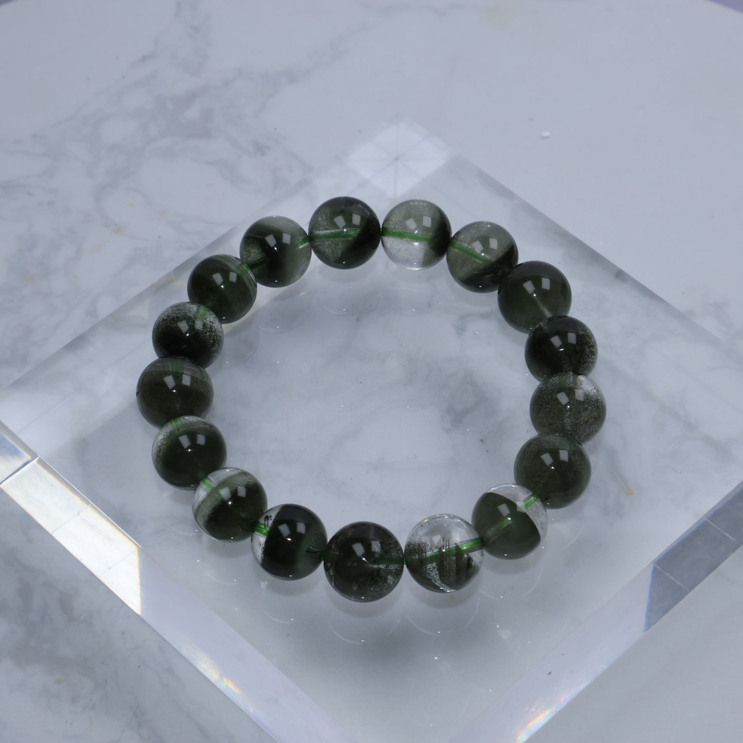 Flat lay of Green Phantom Quartz bracelet on clear acrylic block