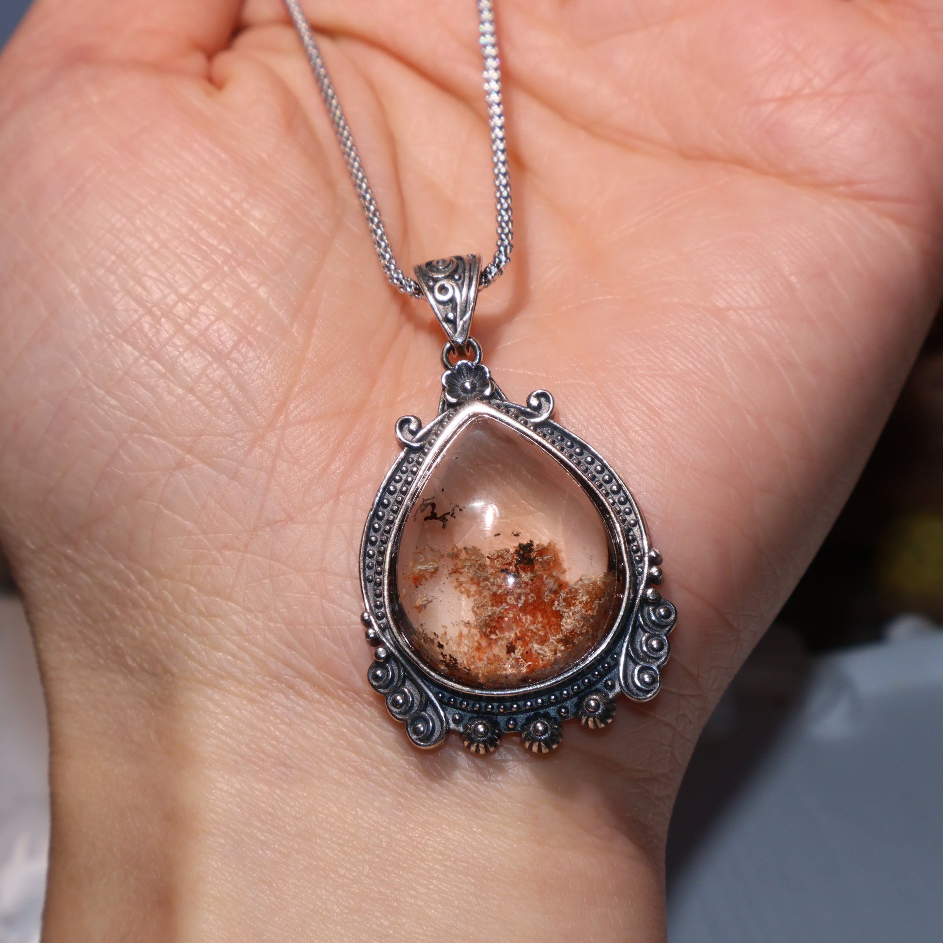 Handheld view showing scale and fine crystal inclusions within the pendant.