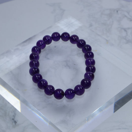 Flat lay of Uruguayan Amethyst bracelet on clear acrylic block