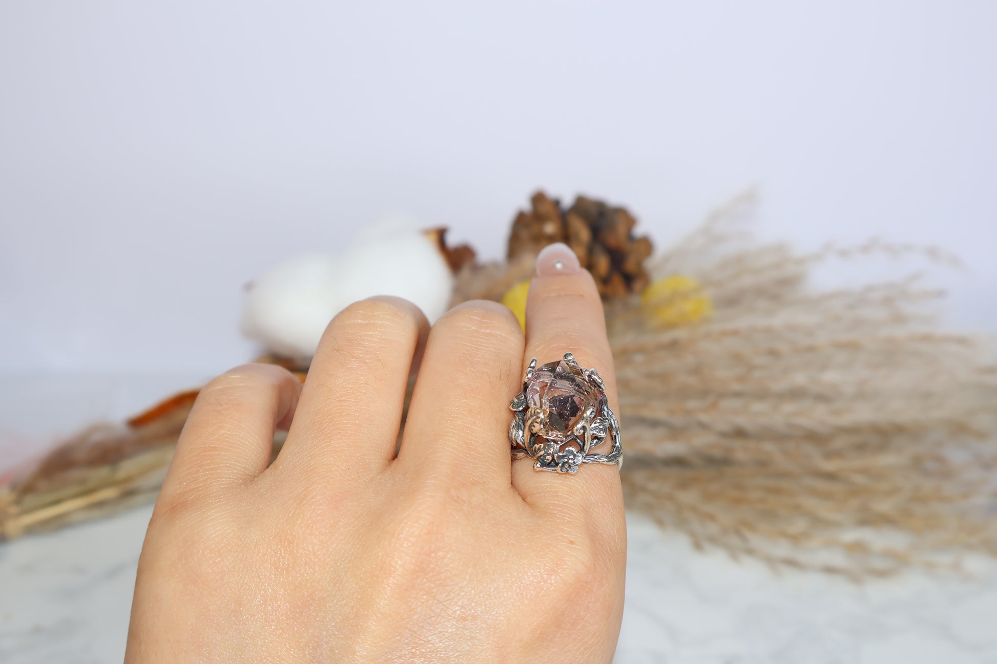 Close-up of the Ametrine gemstone and detailed silver flowerwork held by fingers
