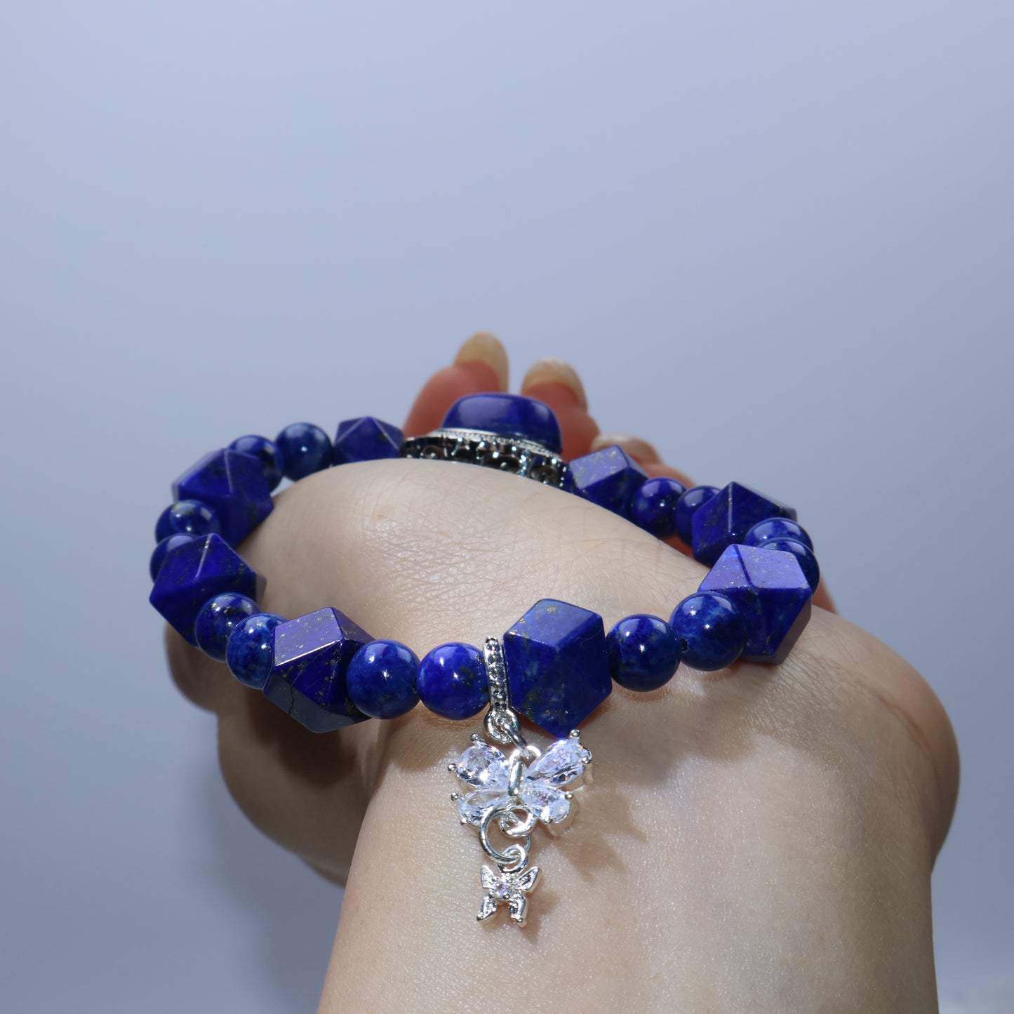 Rear wrist view showing butterfly cubic zirconia charm hanging below Lapis beads