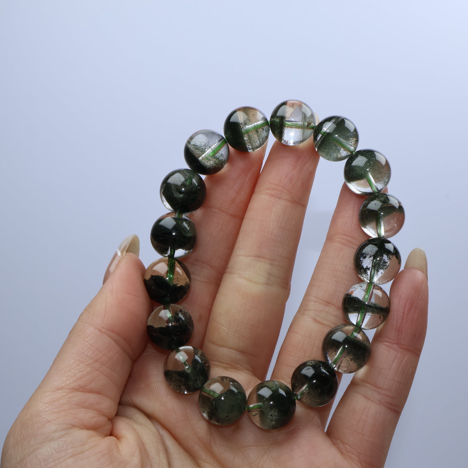 Handheld view of Verdant Path Green Phantom Quartz bracelet showcasing moss-like inclusions