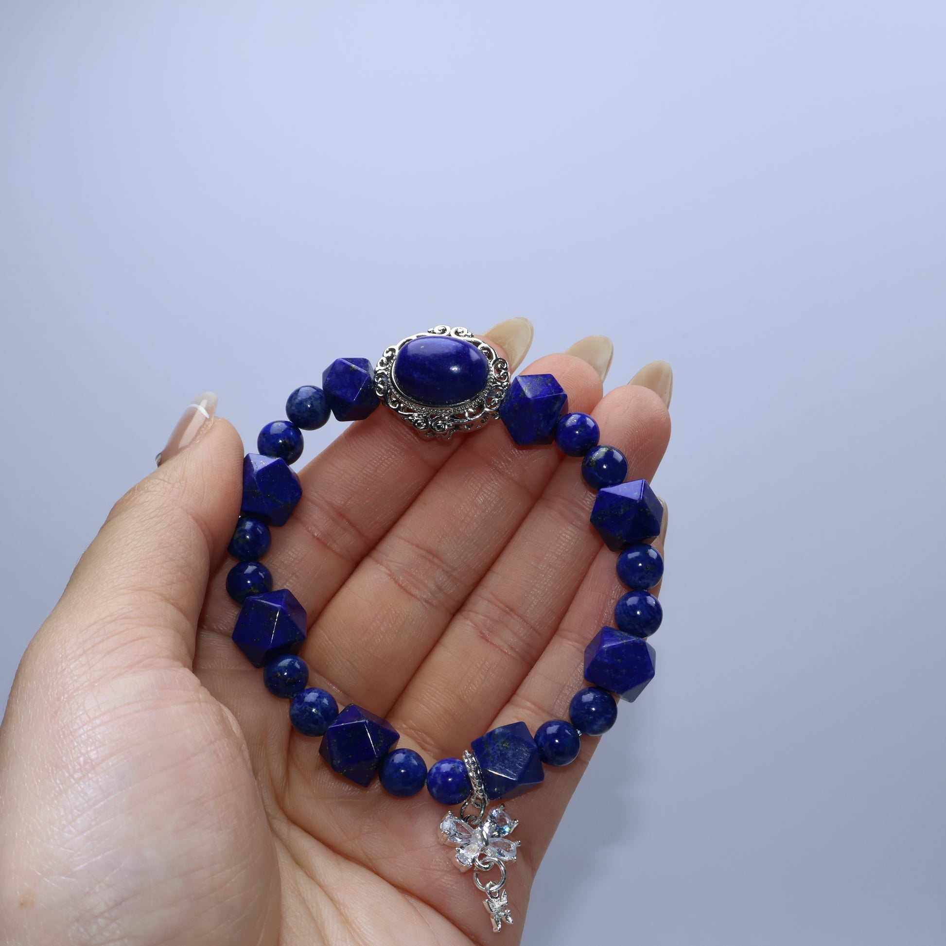 Handheld view showing vintage-style Lapis Lazuli cabochon centerpiece and butterfly charm