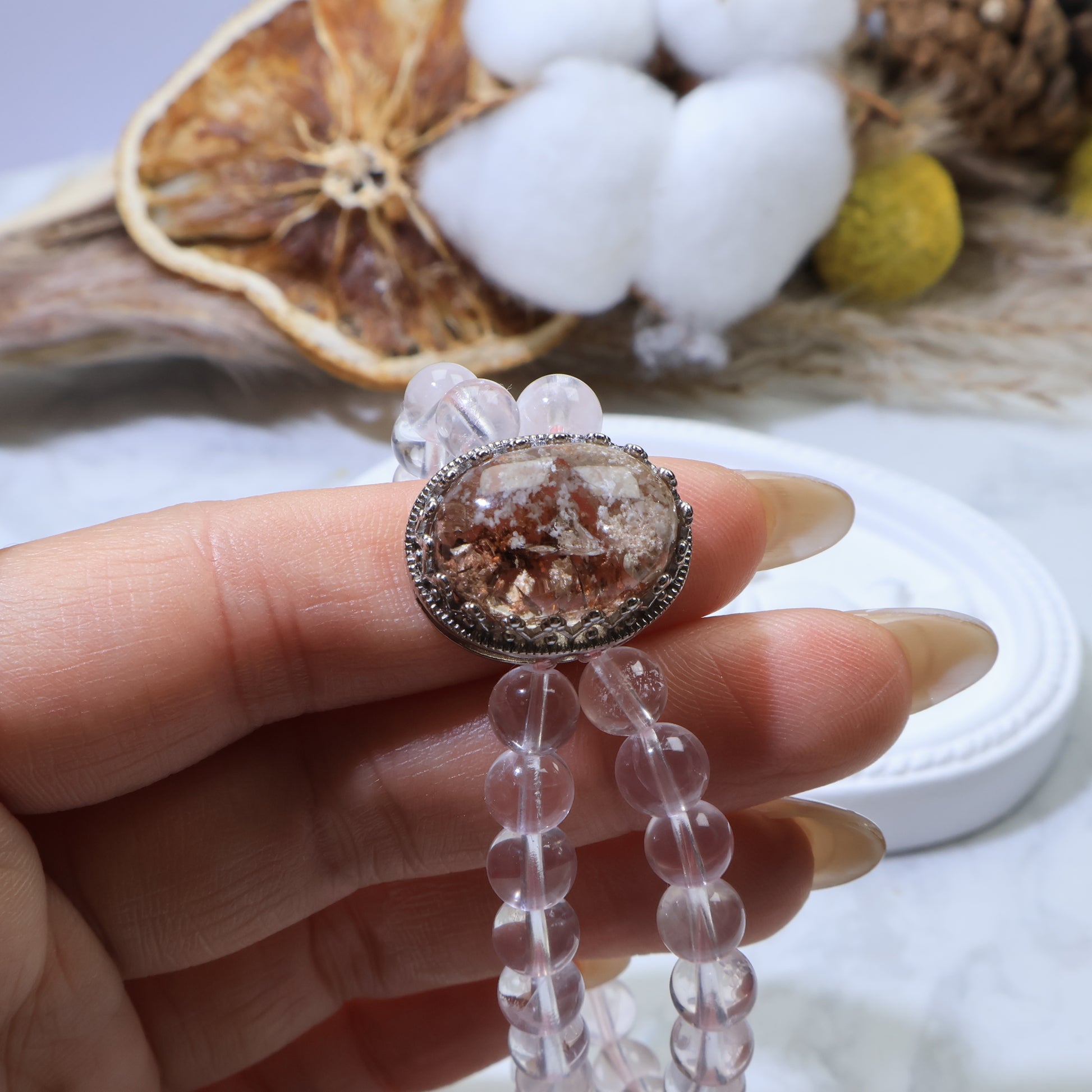 Hand holding the bracelet, highlighting the detailed metal frame around the Phantom Quartz centerpiece