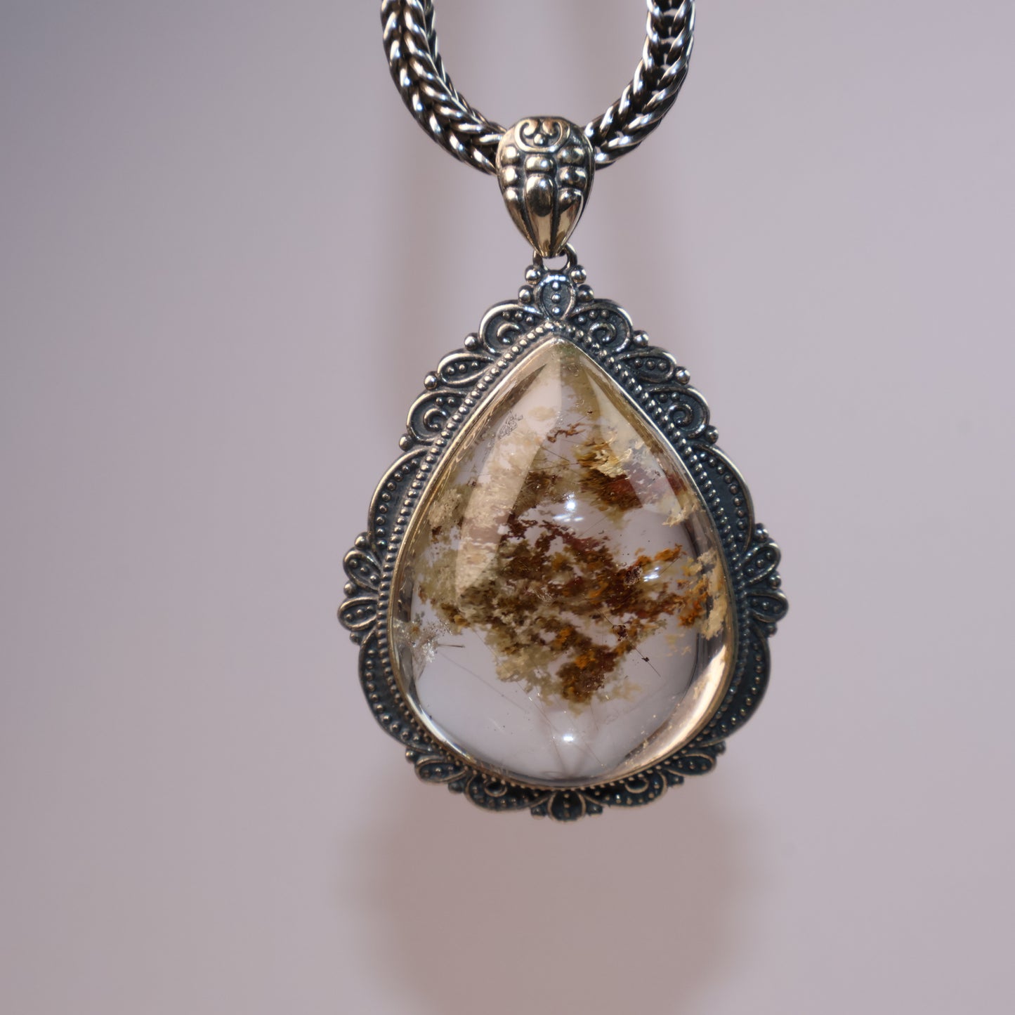Front view of large Phantom Quartz pendant with detailed internal inclusions and hair-like filaments, captured under soft lighting.