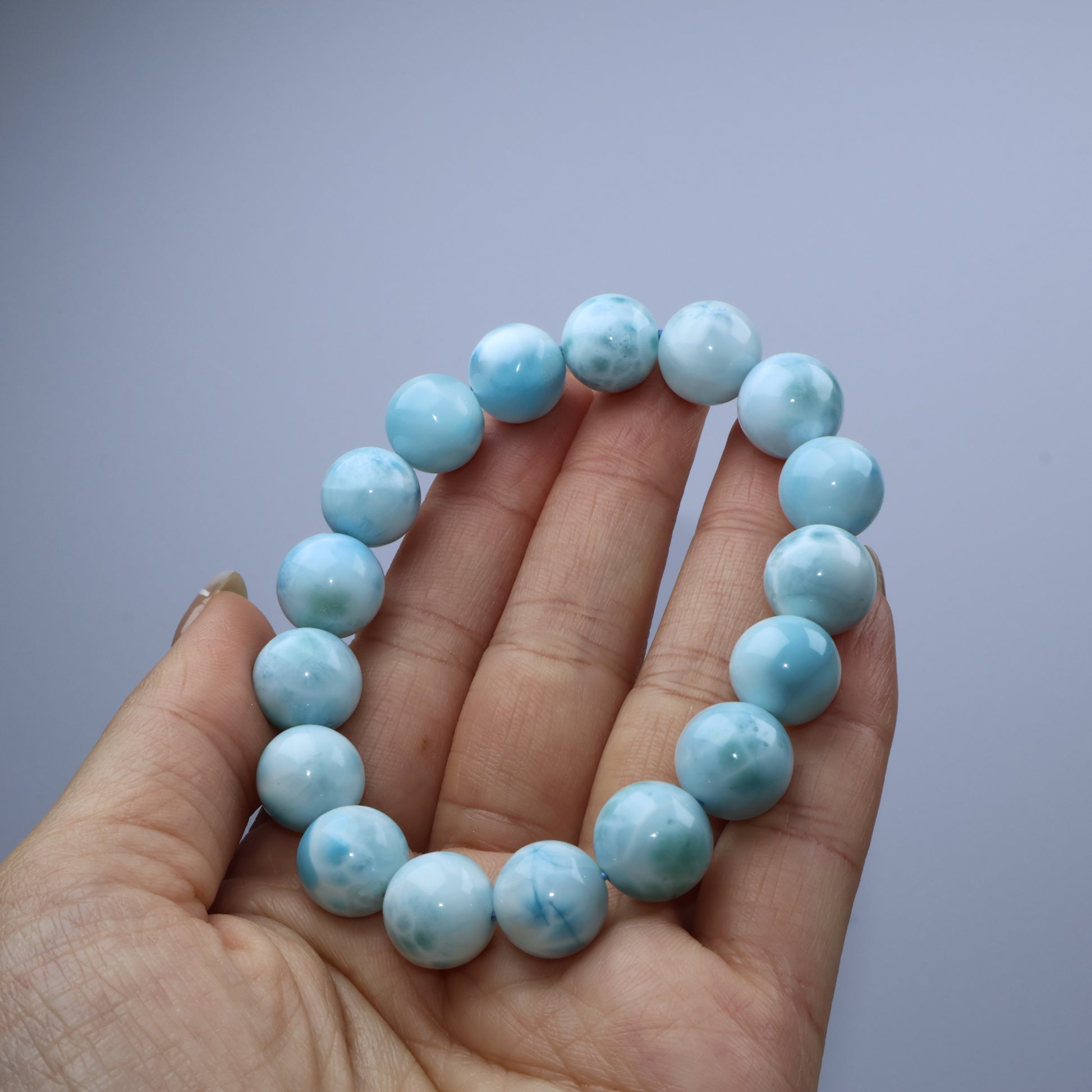 Handheld view of Larimar bracelet emphasizing bead texture and reflection