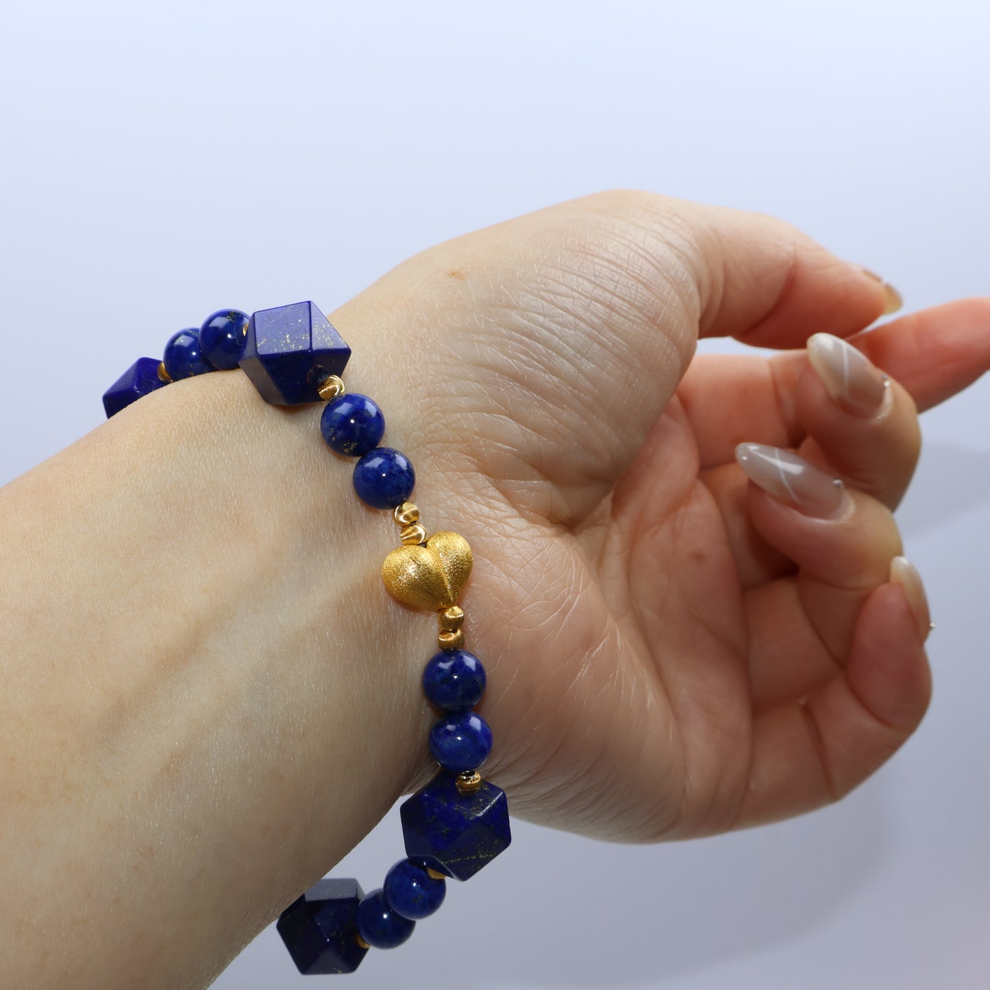 Wrist shot capturing harmony of deep blue lapis and golden elements on skin
