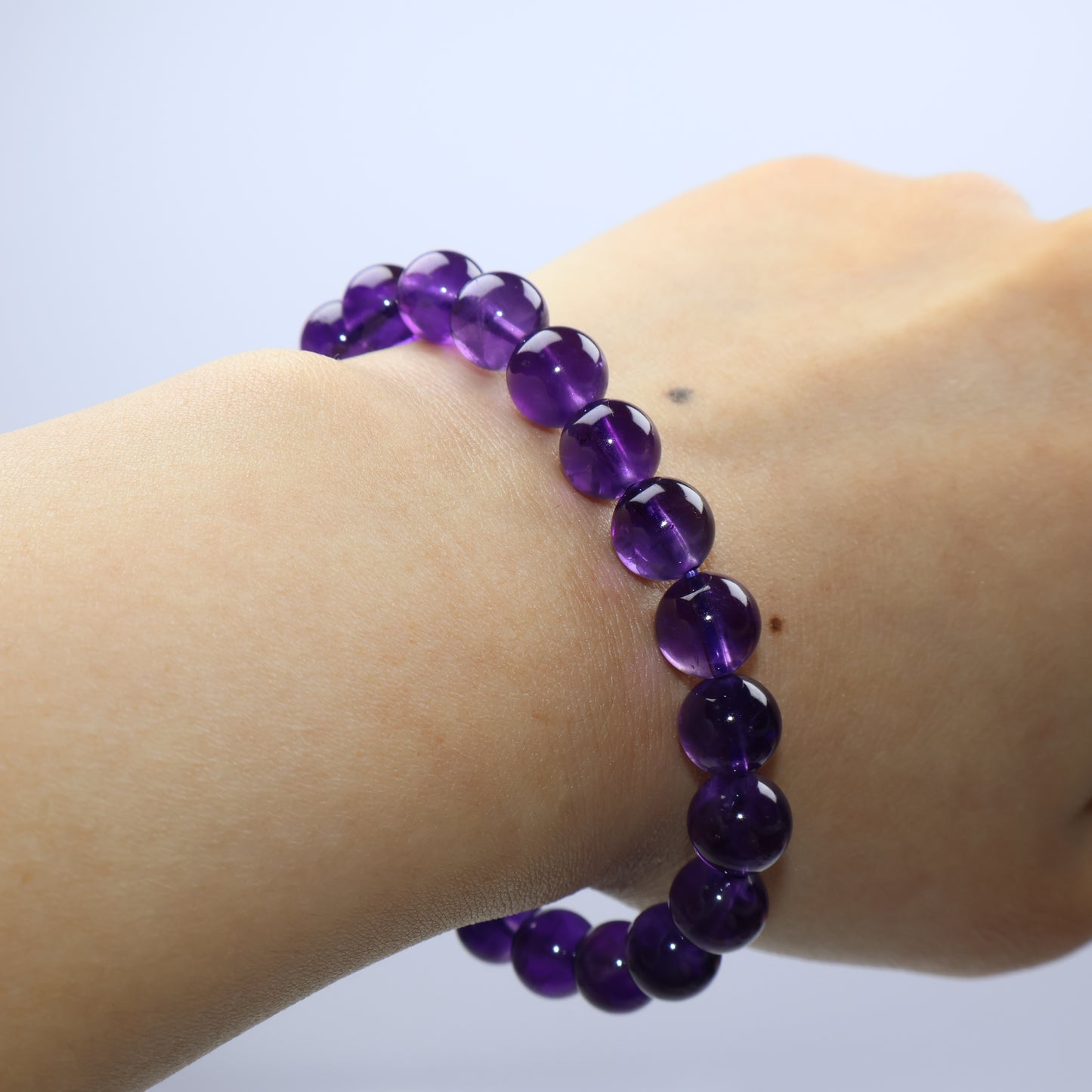 Worn on wrist – glowing violet Amethyst beads with smooth texture